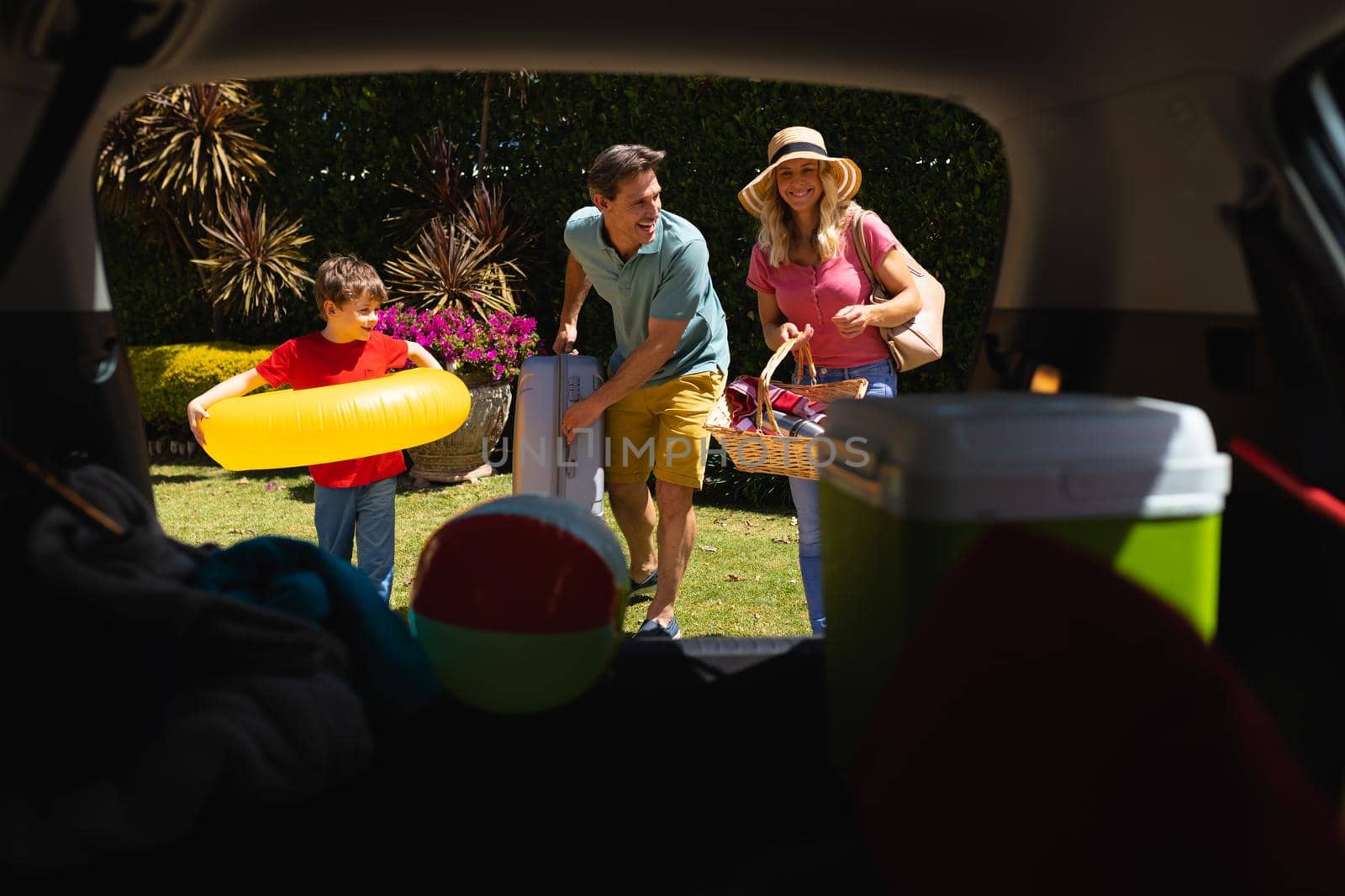 Happy caucasian family putting all their luggage in car. family trip and vacation concept, unaltered.