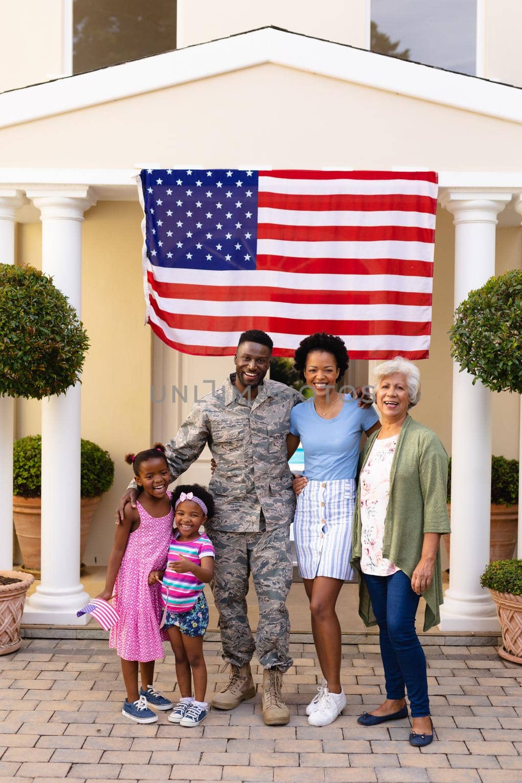 Portrait of smiling african american family with army soldier at entrance against usa flag by Wavebreakmedia