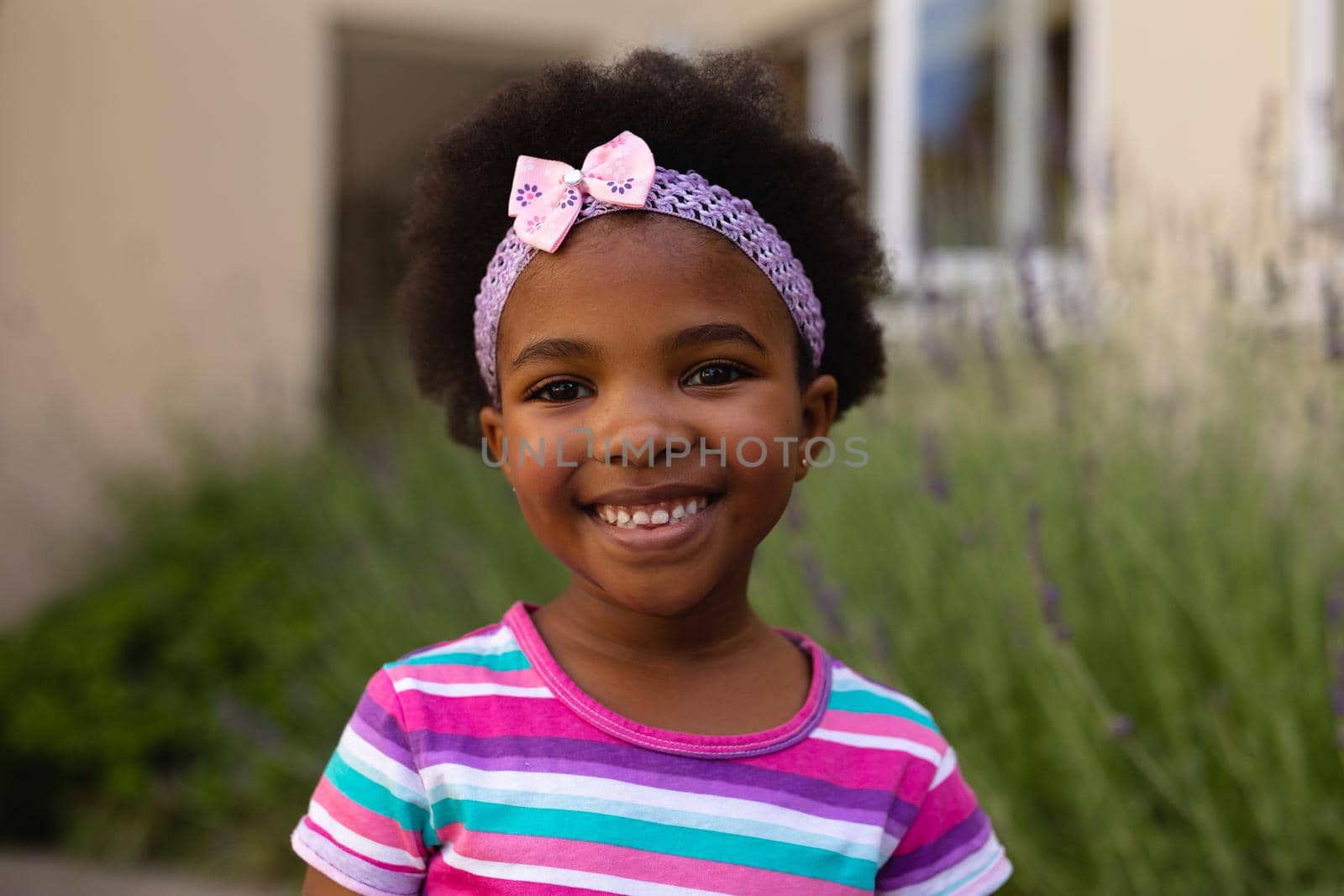 Portrait of smiling cute african american girl wearing headband and striped t-shirt. childhood and innocence, unaltered.