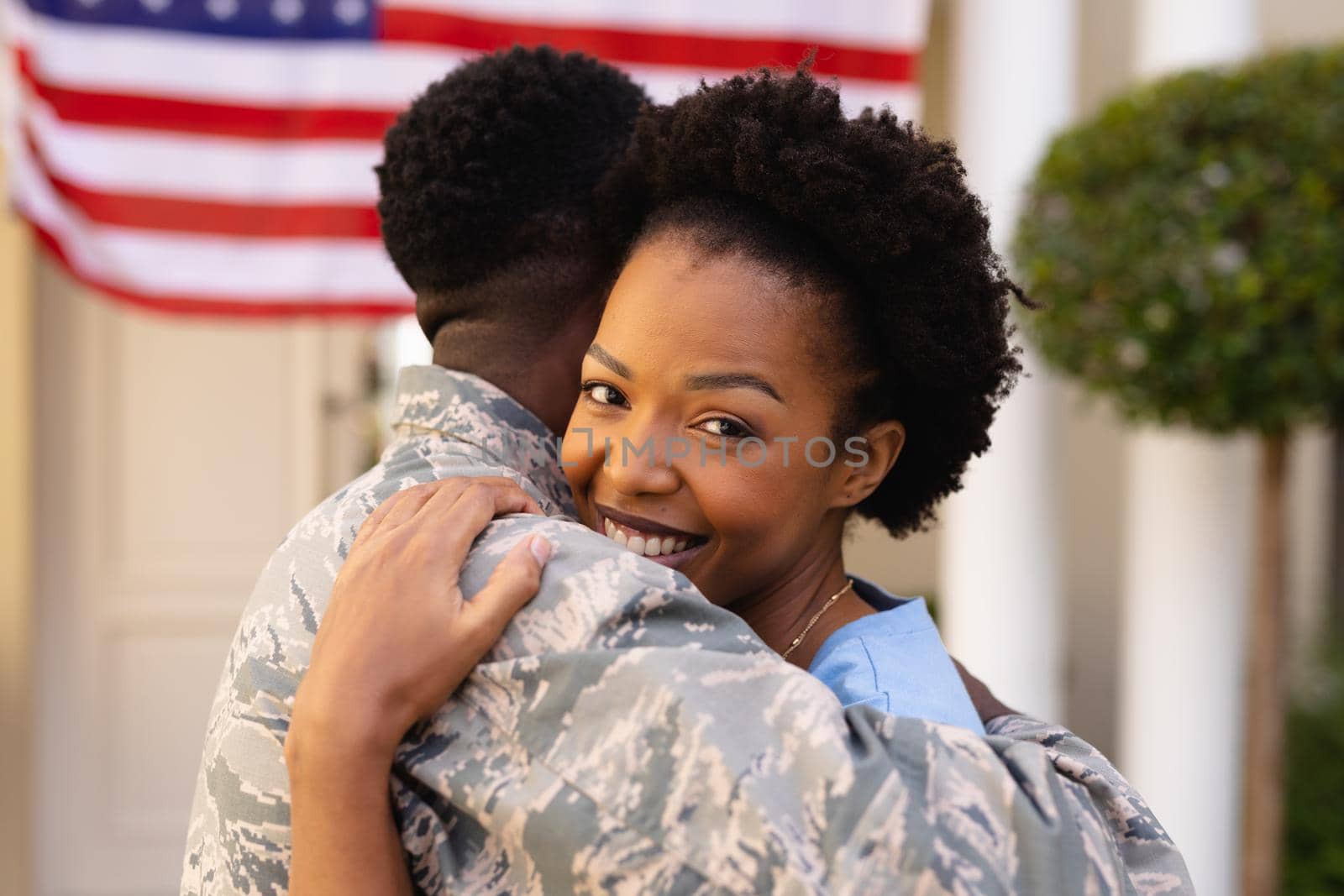 Portrait of smiling african american hugging military soldier on his return home. togetherness, bonding and patriotism, unaltered.