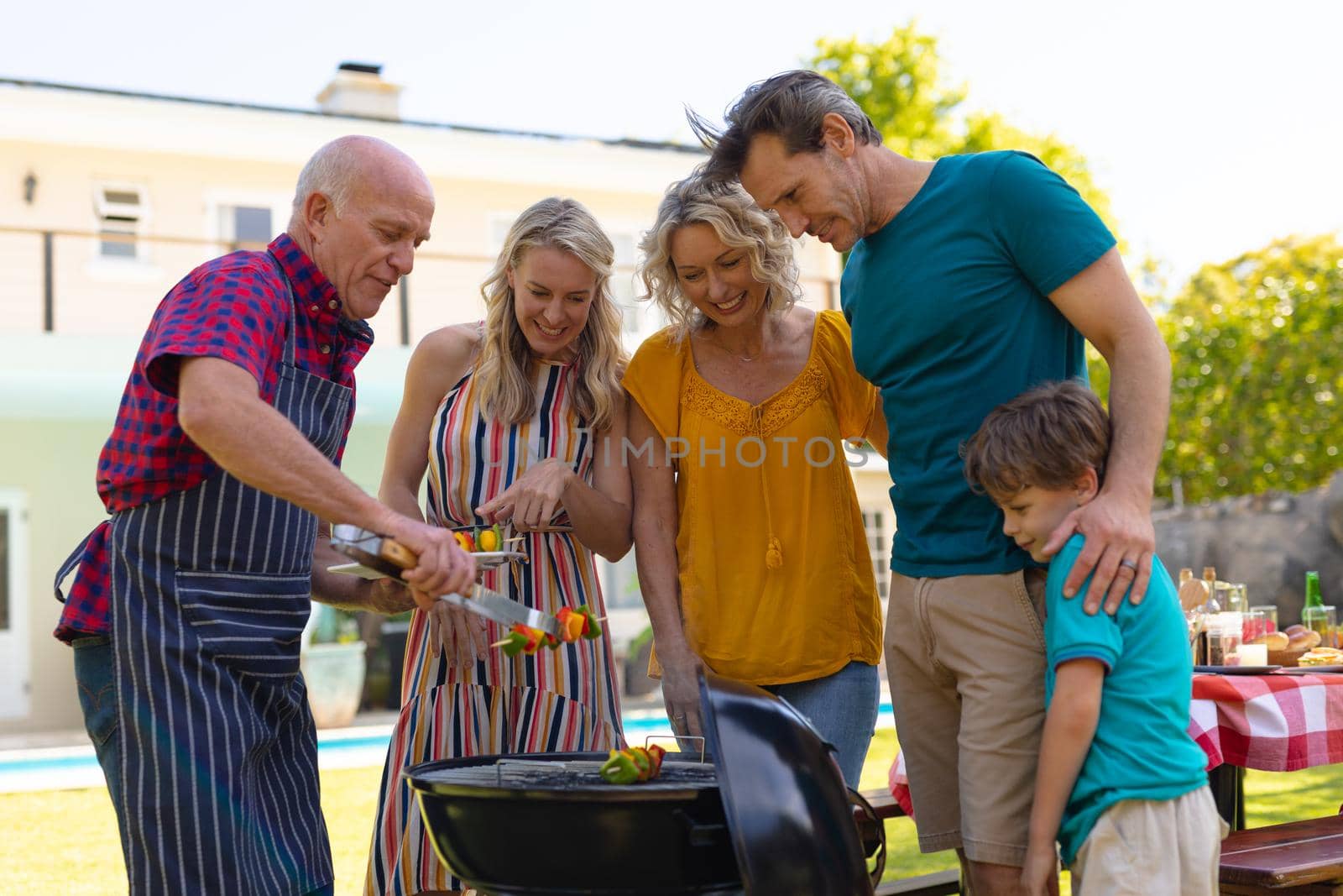 Three generational caucasian family barbecuing together in the garden. family, togetherness and weekend lifestyle concept, unaltered.