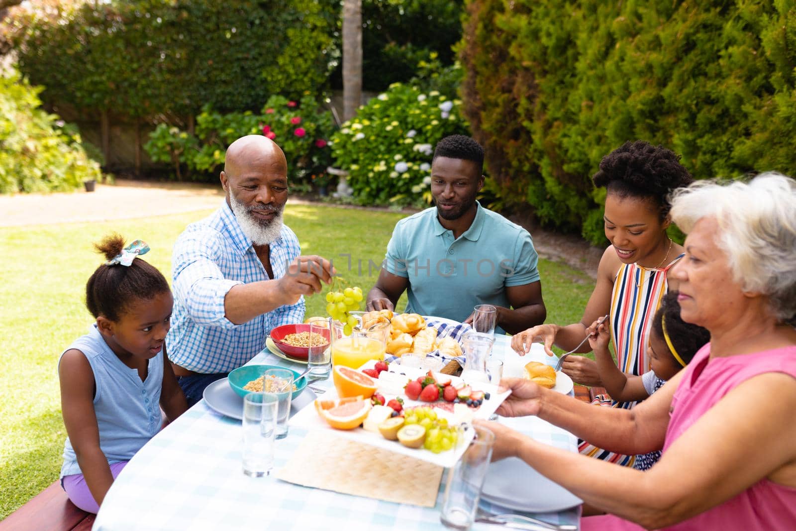 African american family enjoying brunch at table in backyard. family, love and togetherness concept, unaltered.