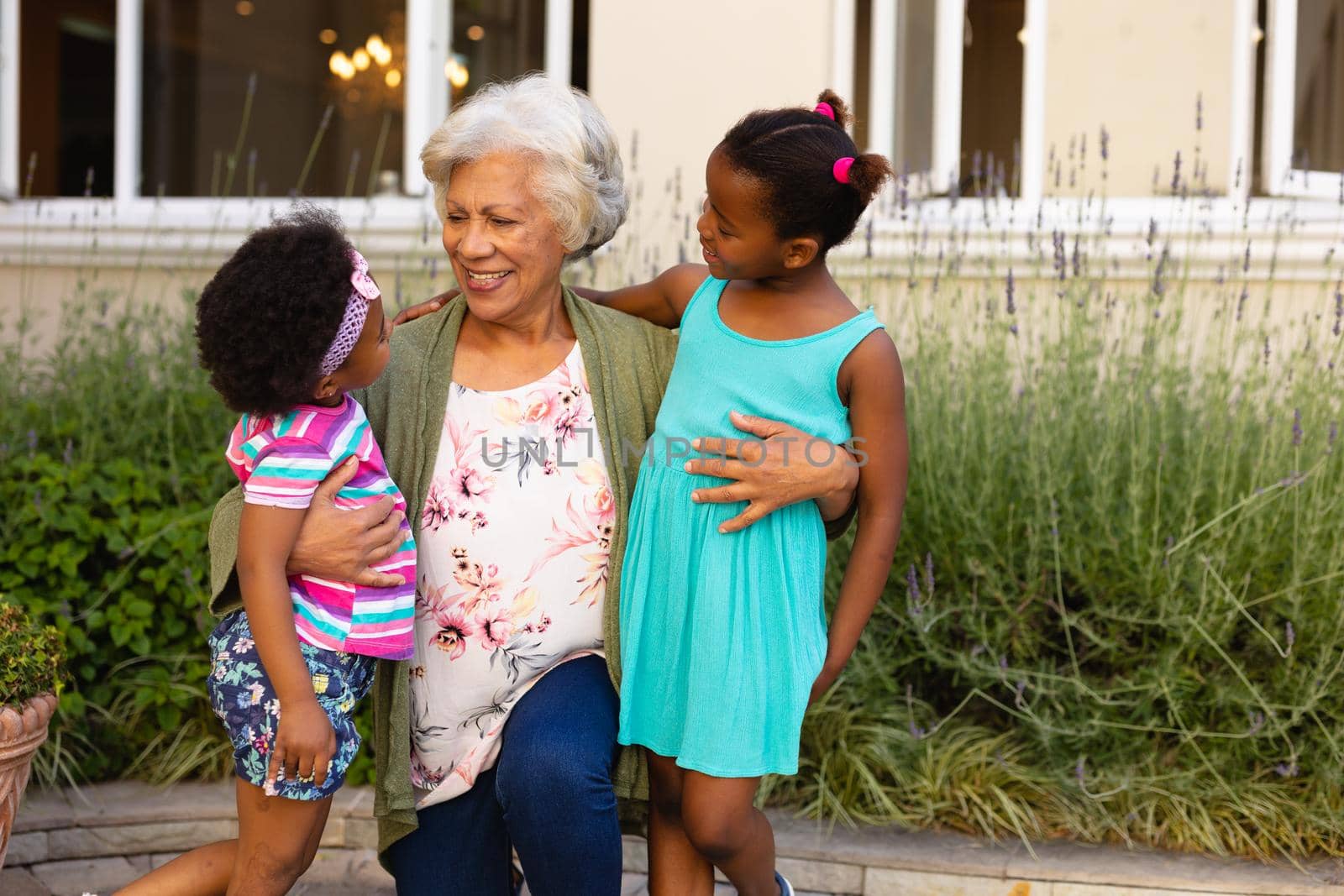 African american grandmother looking at her granddaughters and smiling outdoors. family, love and togetherness concept, unaltered.