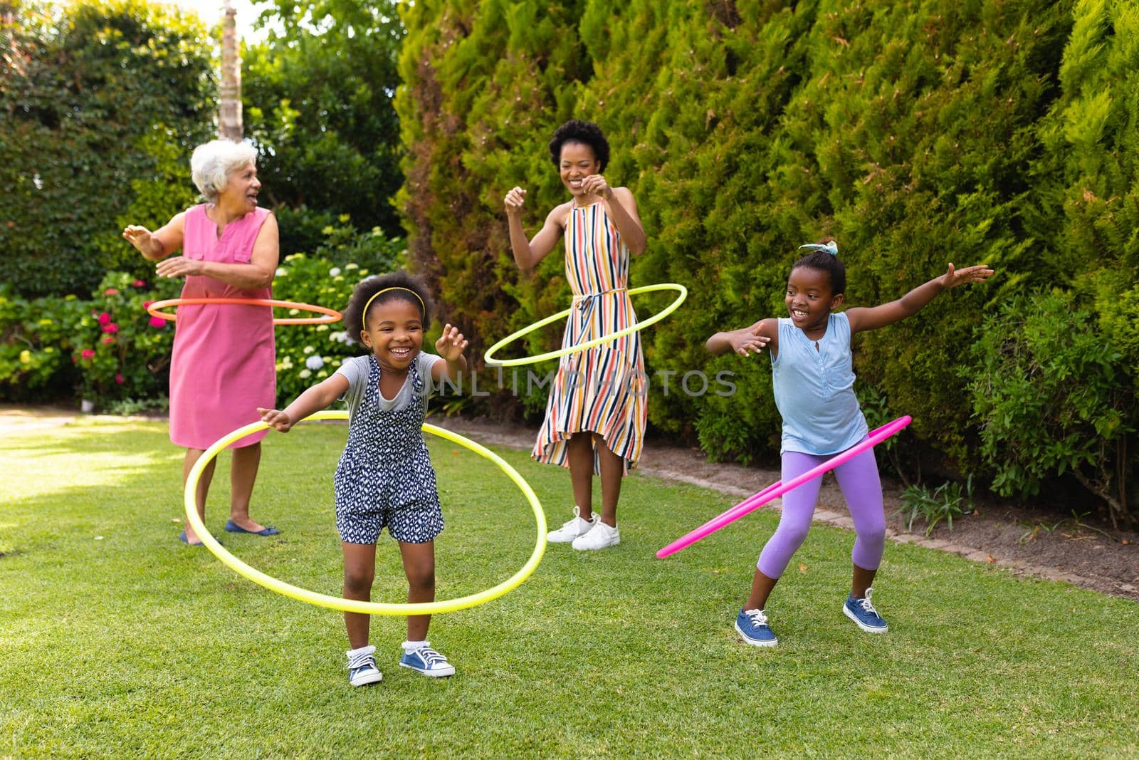 Playful african american family enjoying with plastic hoops at backyard garden by Wavebreakmedia