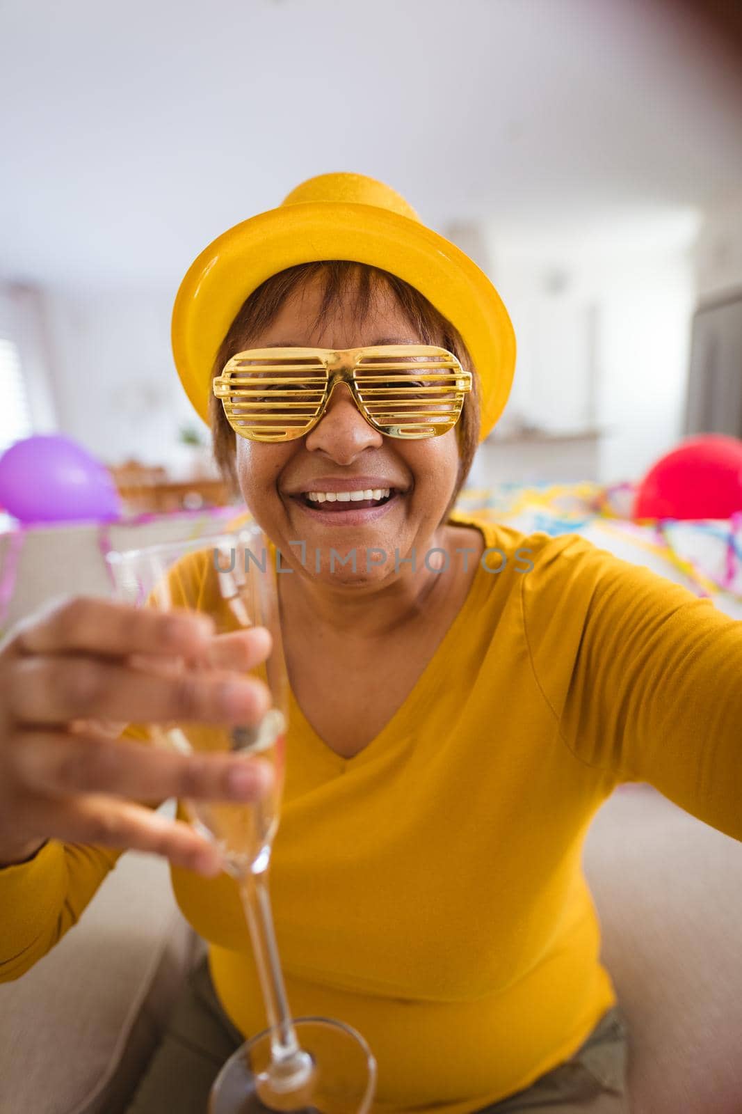 Happy senior woman in shutter glasses doing video call while enjoying champagne during party at home by Wavebreakmedia