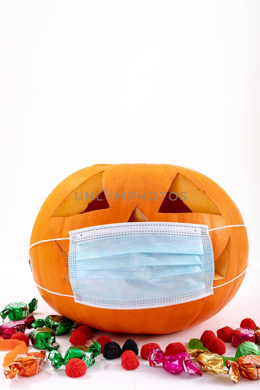 Halloween jack o lantern with face mask on white background with sweets by Wavebreakmedia