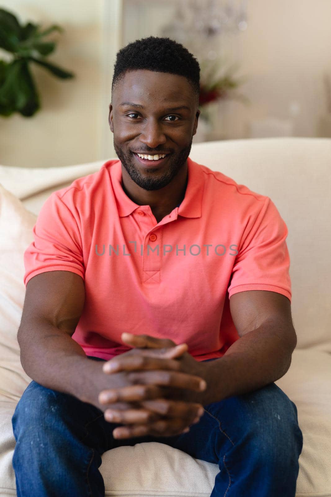 Portrait of african american man smiling while sitting on the couch at home by Wavebreakmedia