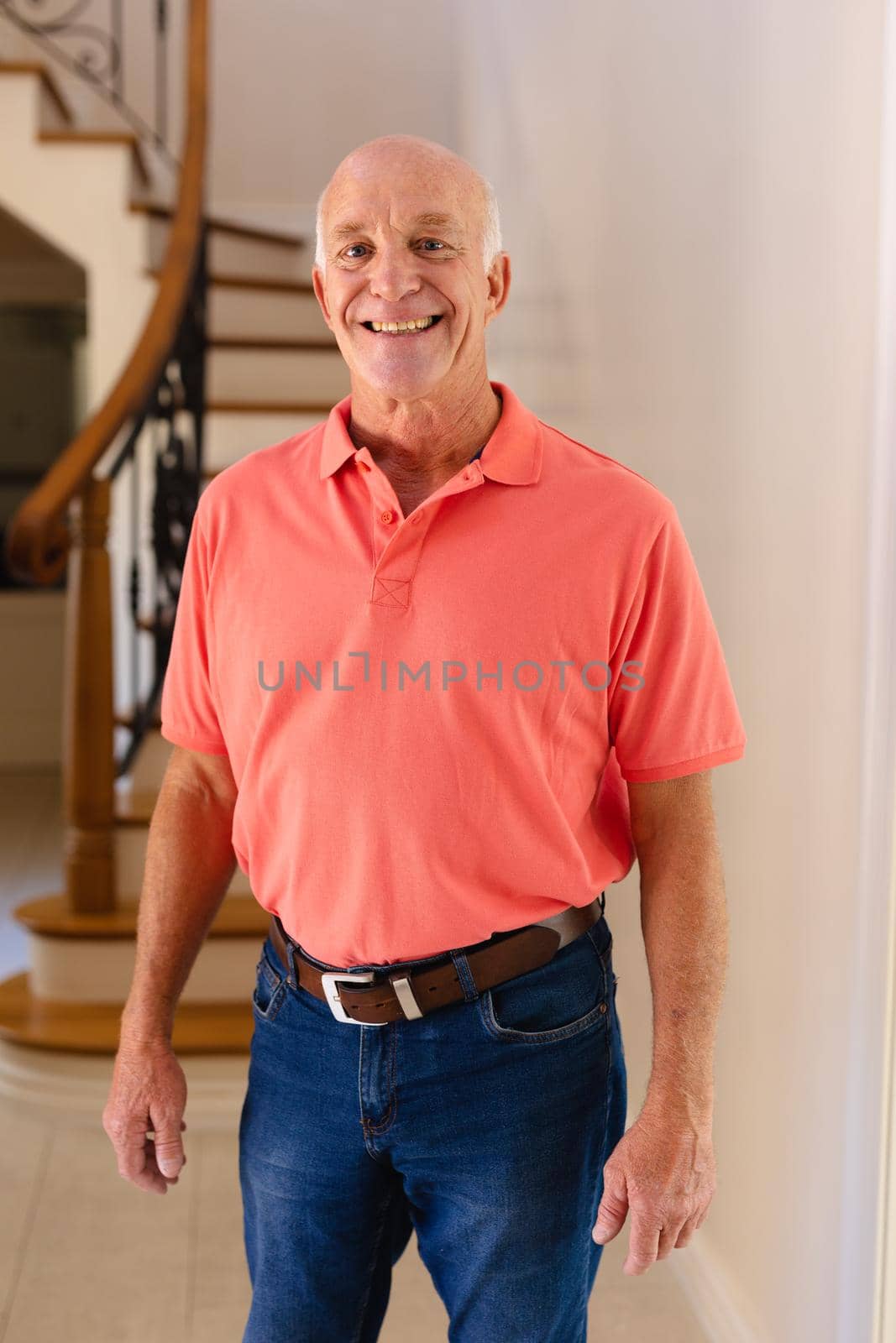 Portrait of caucasian senior man smiling while standing in the living room at home by Wavebreakmedia