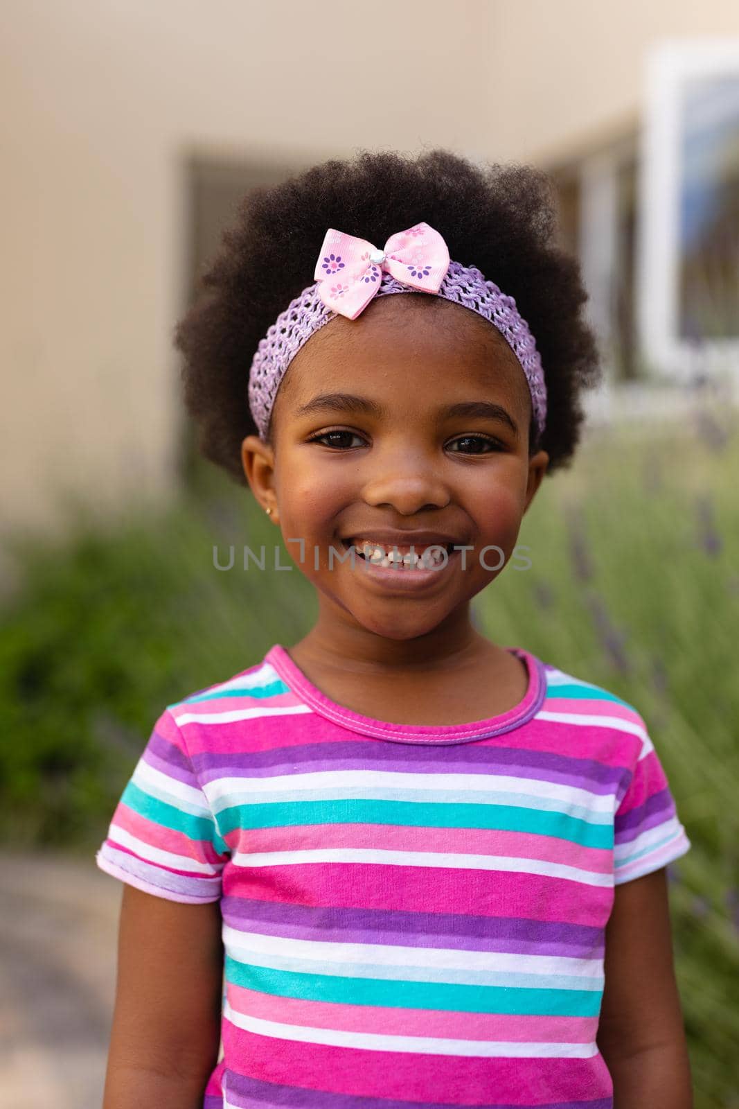 Portrait of smiling cute african american girl wearing striped t-shirt and headband by Wavebreakmedia