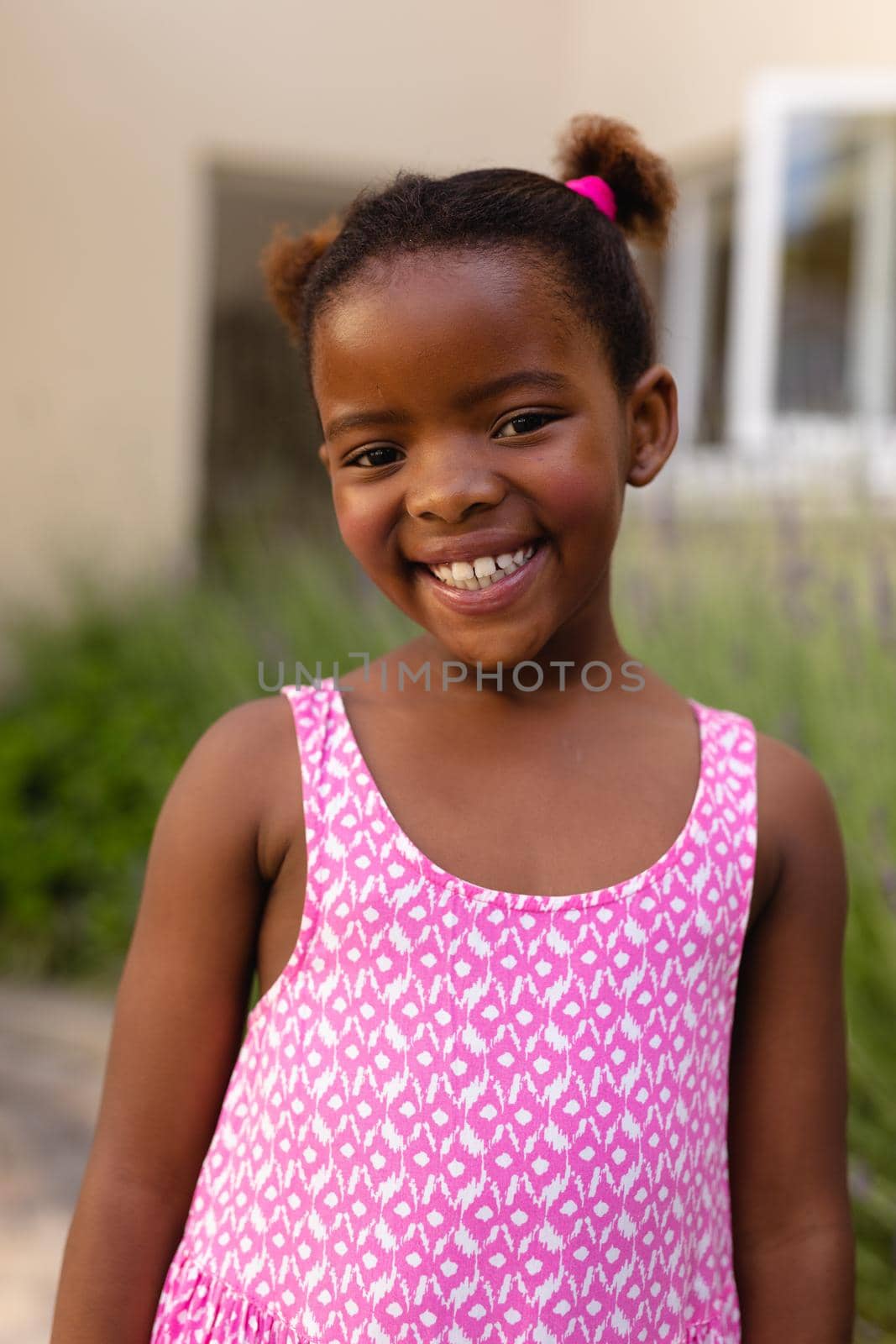 Portrait of smiling cute african american girl wearing pink sleeveless top. childhood and innocence, unaltered.