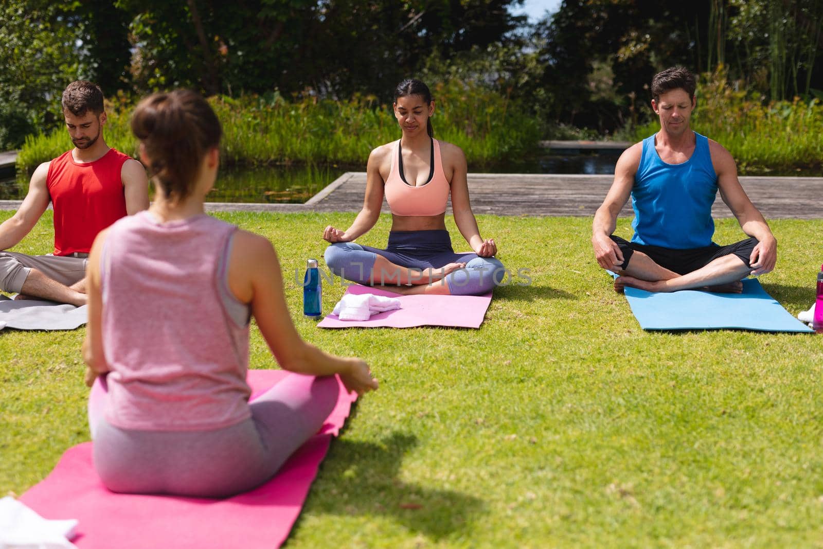 Female instructor teaching meditation to men and woman in park by Wavebreakmedia