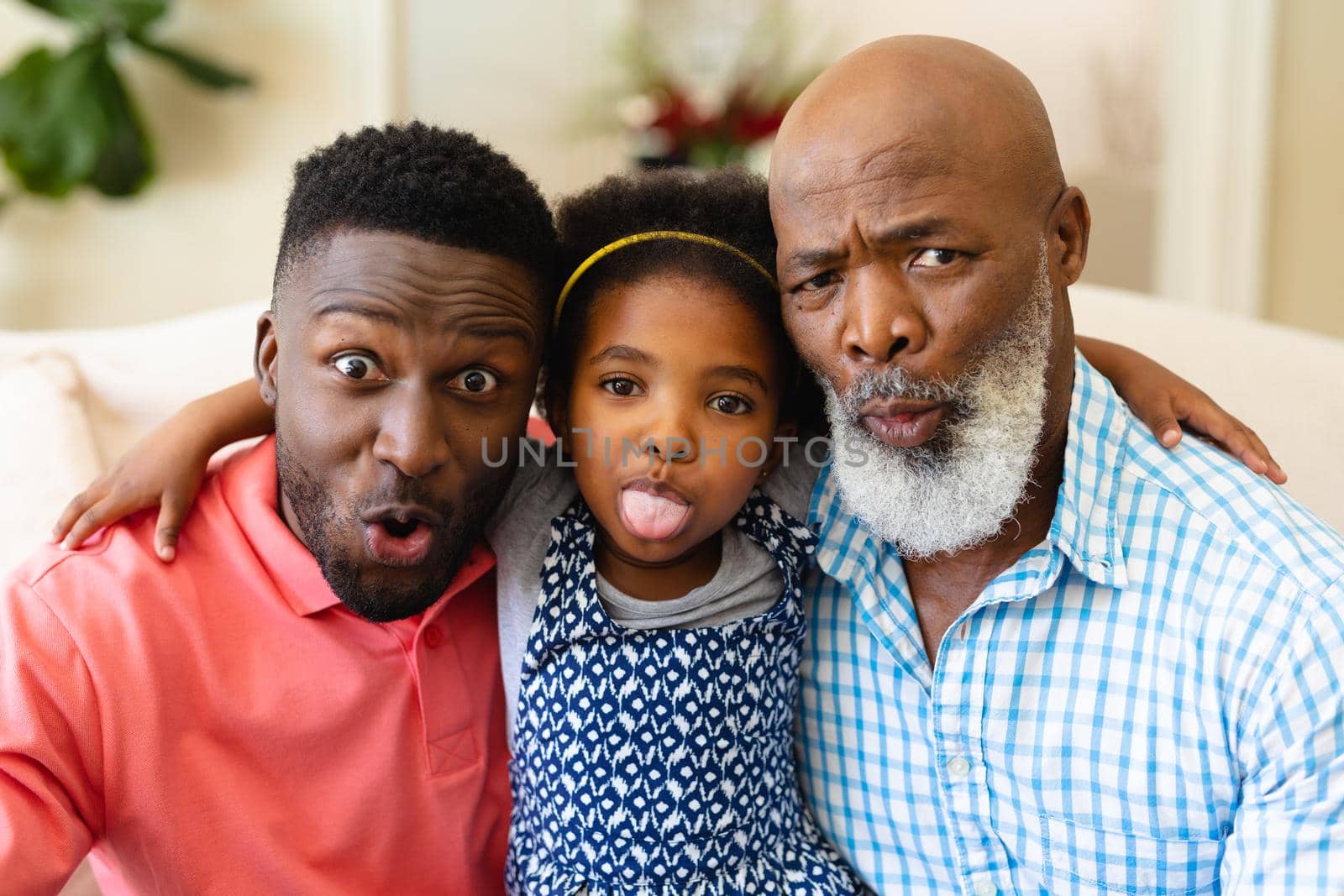 Portrait of african american grandfather, father and granddaughter making silly faces at home by Wavebreakmedia