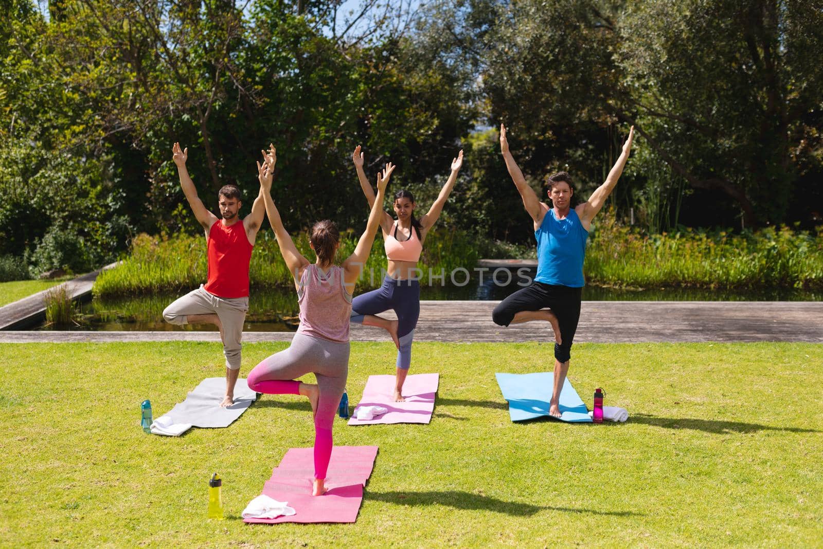 Female instructor teaching yoga to men and woman in park. healthy lifestyle and body care.