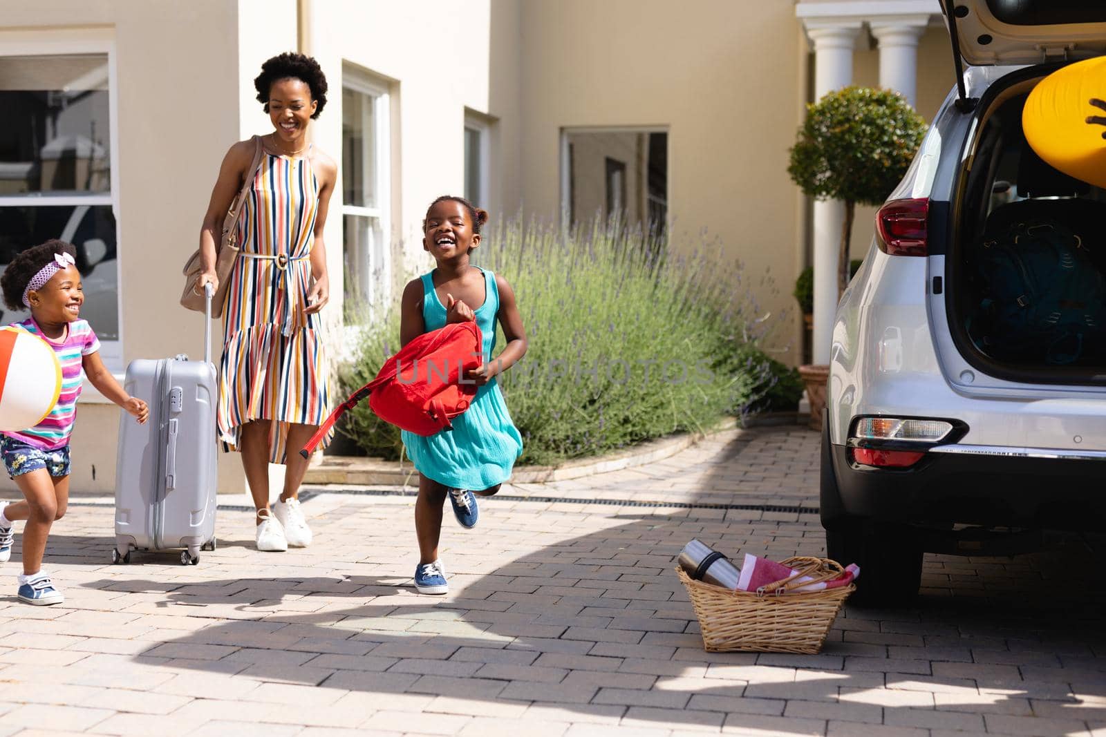 African american mother and her daughters walking towards their car outdoors by Wavebreakmedia