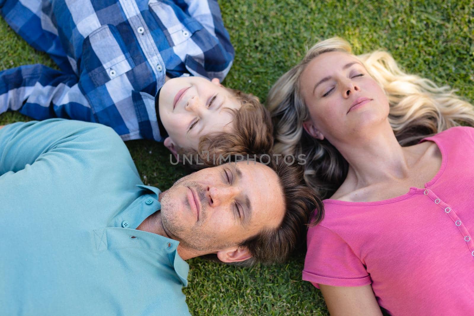 Overhead view of caucasian family lying together in the garden. family, love and togetherness concept, unaltered.