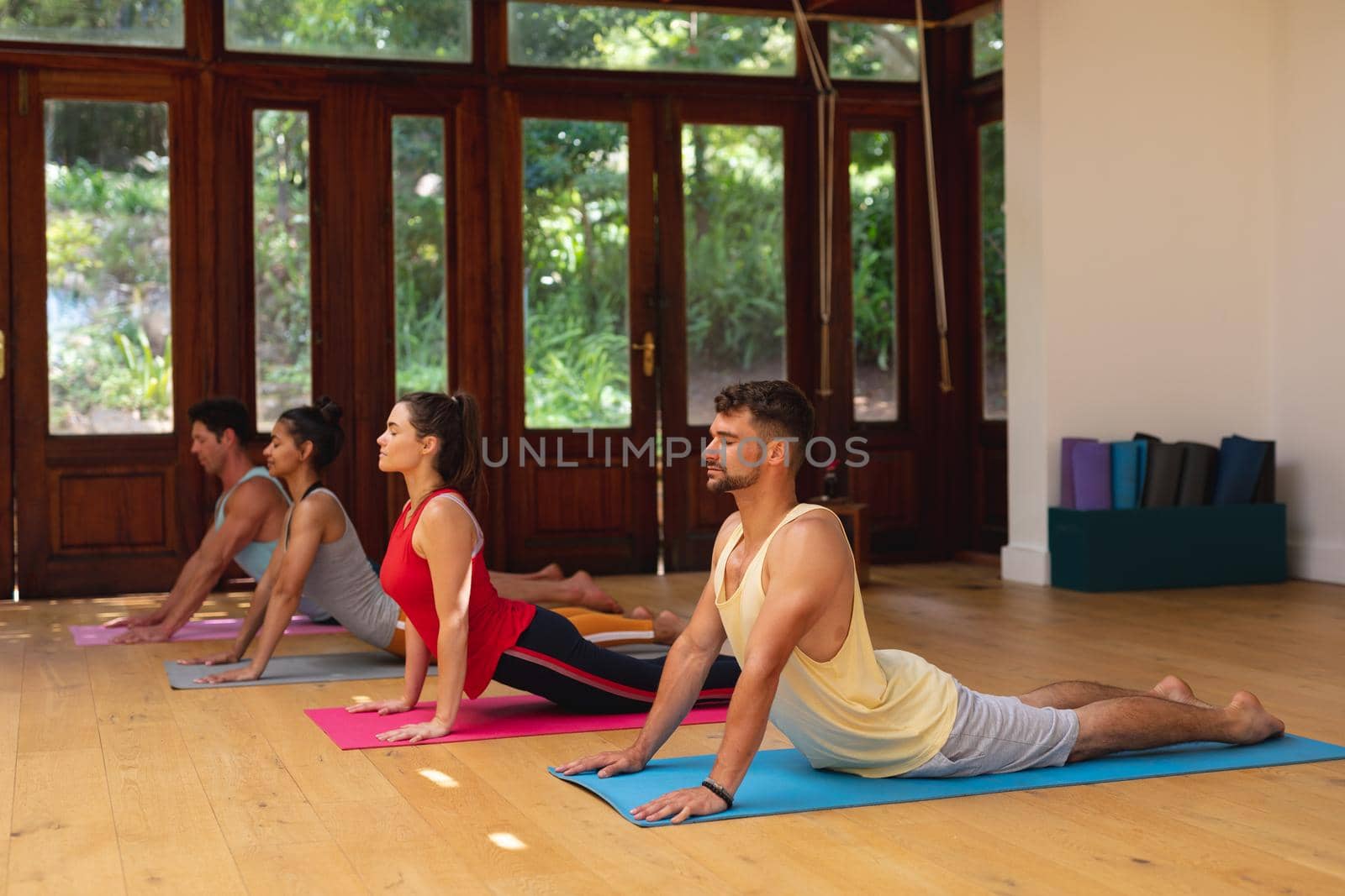 Men and women practicing yoga pose during exercise class at health club by Wavebreakmedia