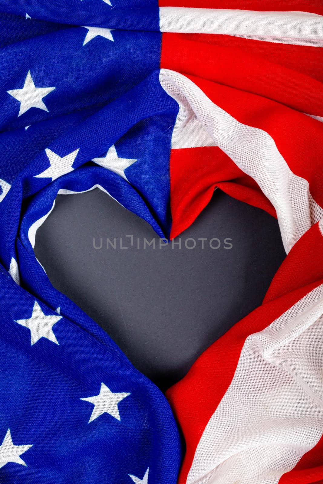 Overhead view of crumpled usa flag making heart shape on black table. patriotism, love and copy space.