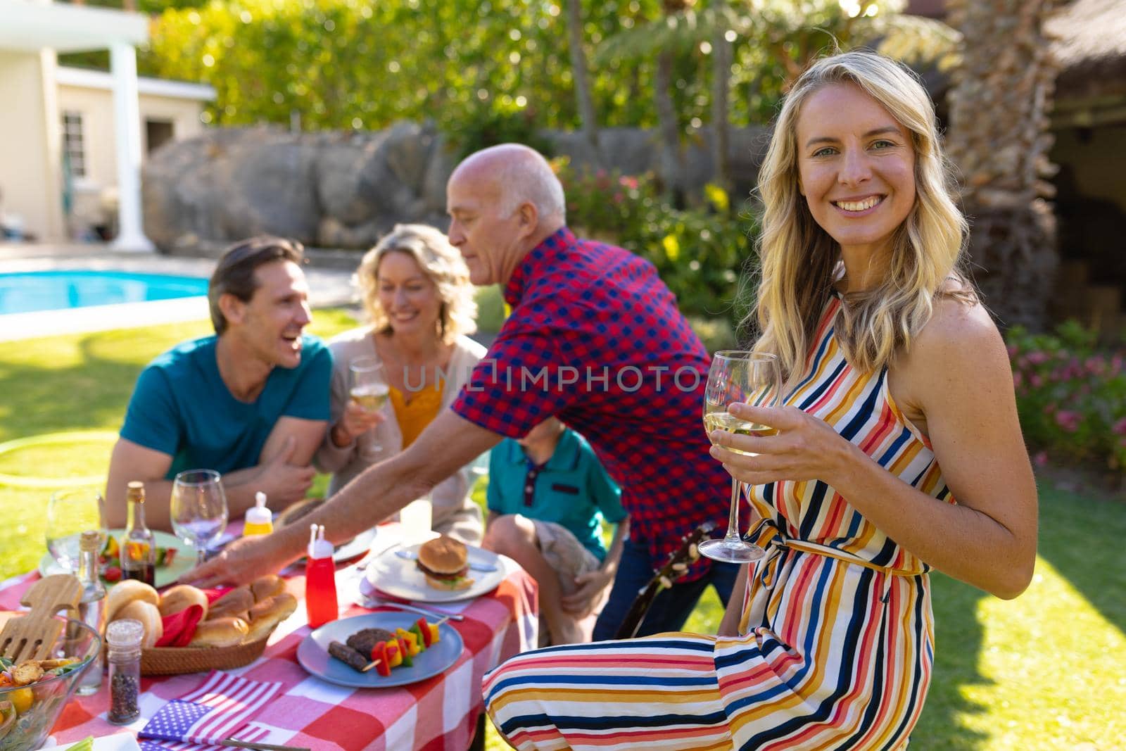 Portrait of smiling caucasian woman with family eating lunch in the garden. family, togetherness and weekend lifestyle concept, unaltered.