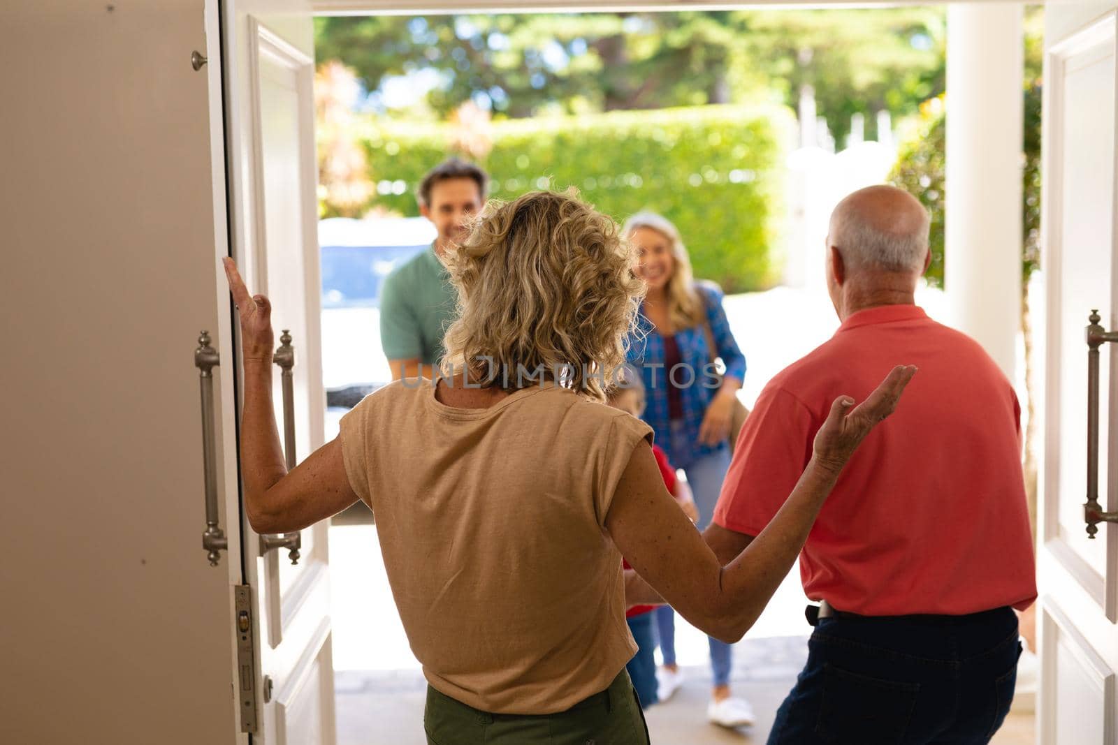 Rear view of caucasian senior couple welcoming their family at the entrance of the house. family, love and togetherness concept, unaltered.