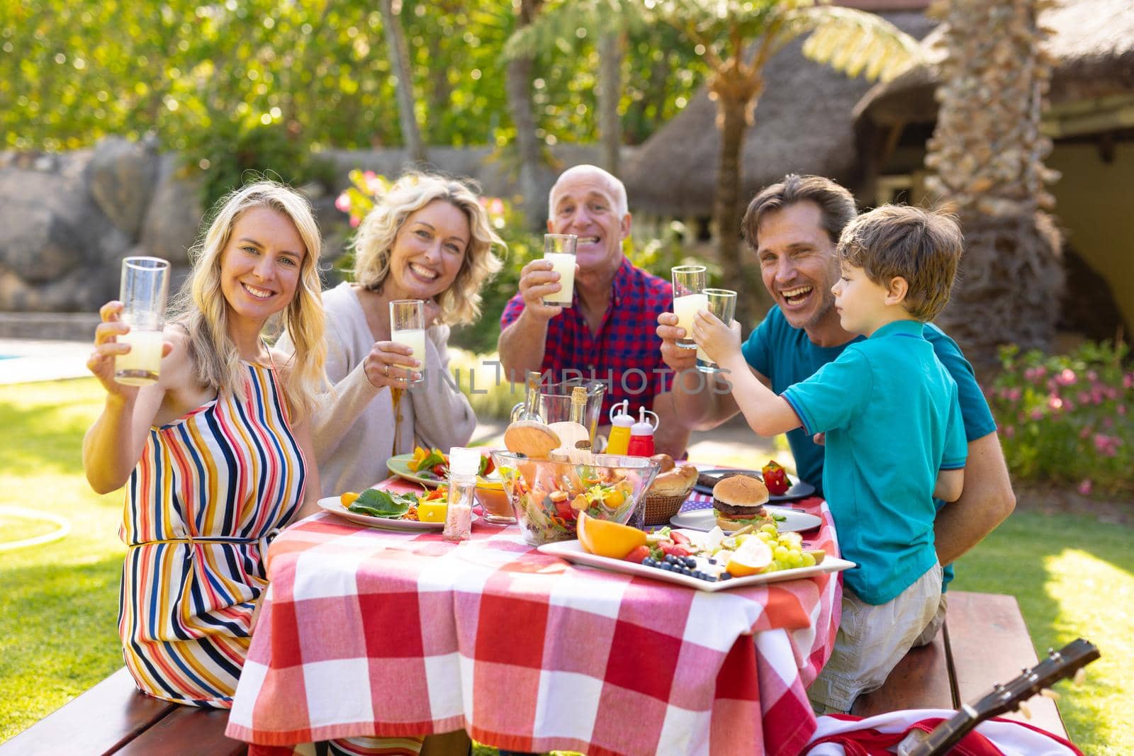 Portrait of happy three generational family toasting drinks at table in the garden. family, togetherness and weekend lifestyle concept, unaltered.