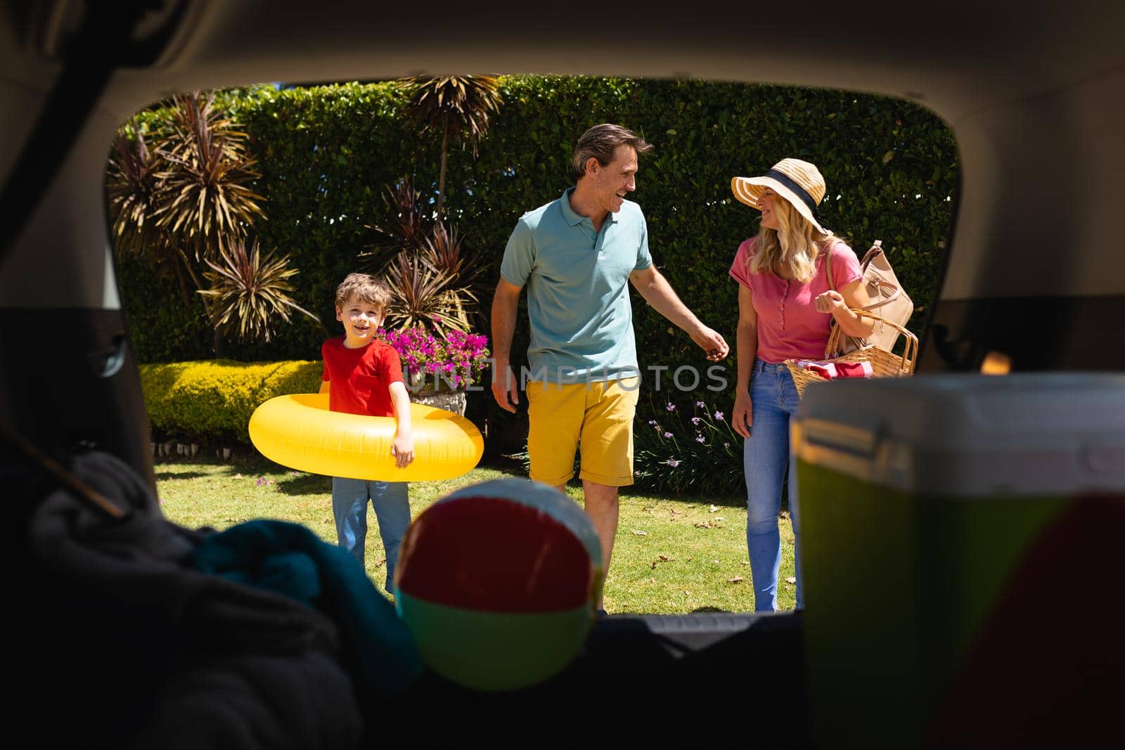 Happy caucasian family putting all their luggage in car on sunny day. family trip and vacation concept, unaltered.