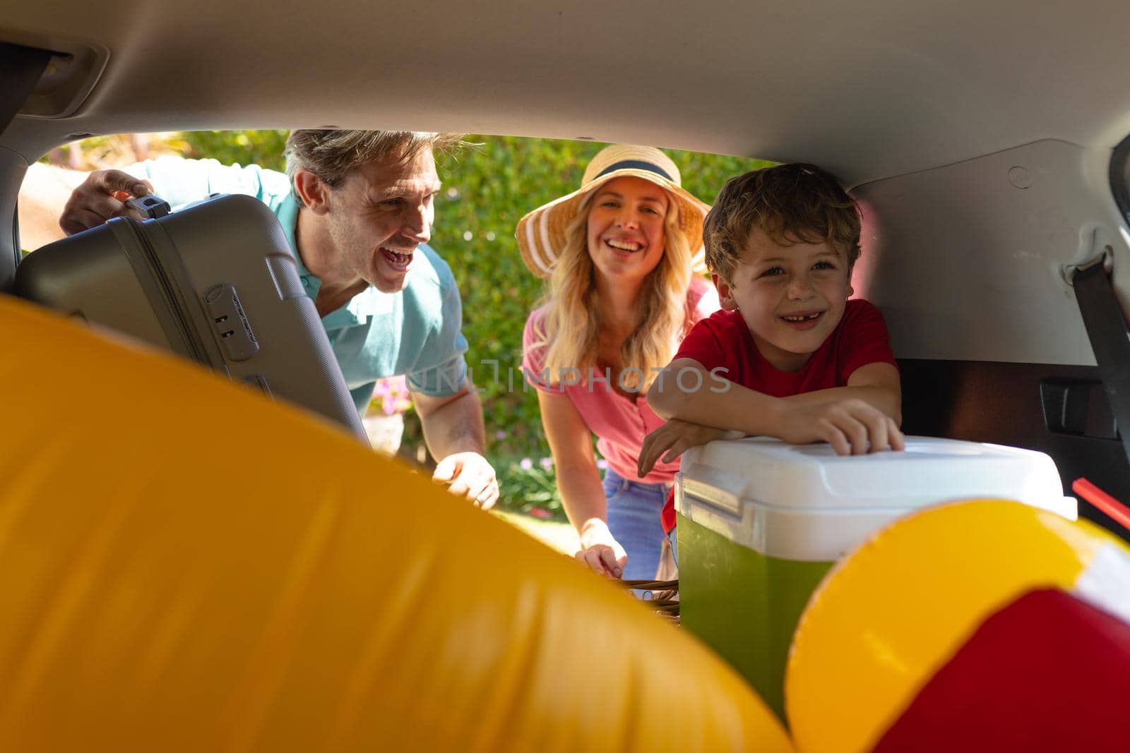 Happy caucasian family putting their luggage in their car. family trip and vacation concept, unaltered.