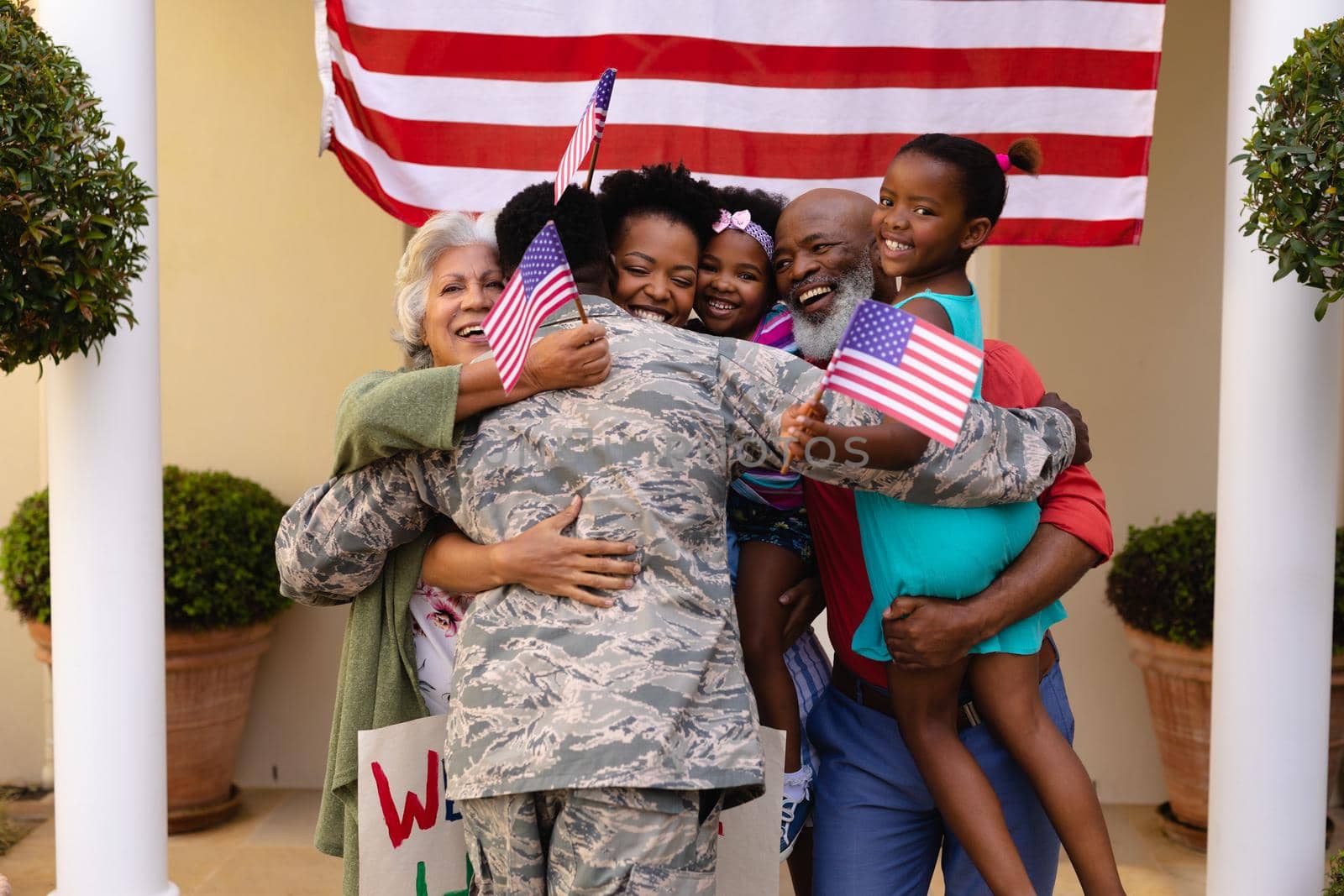 Happy african american family with usa flag hugging army soldier on his return home by Wavebreakmedia