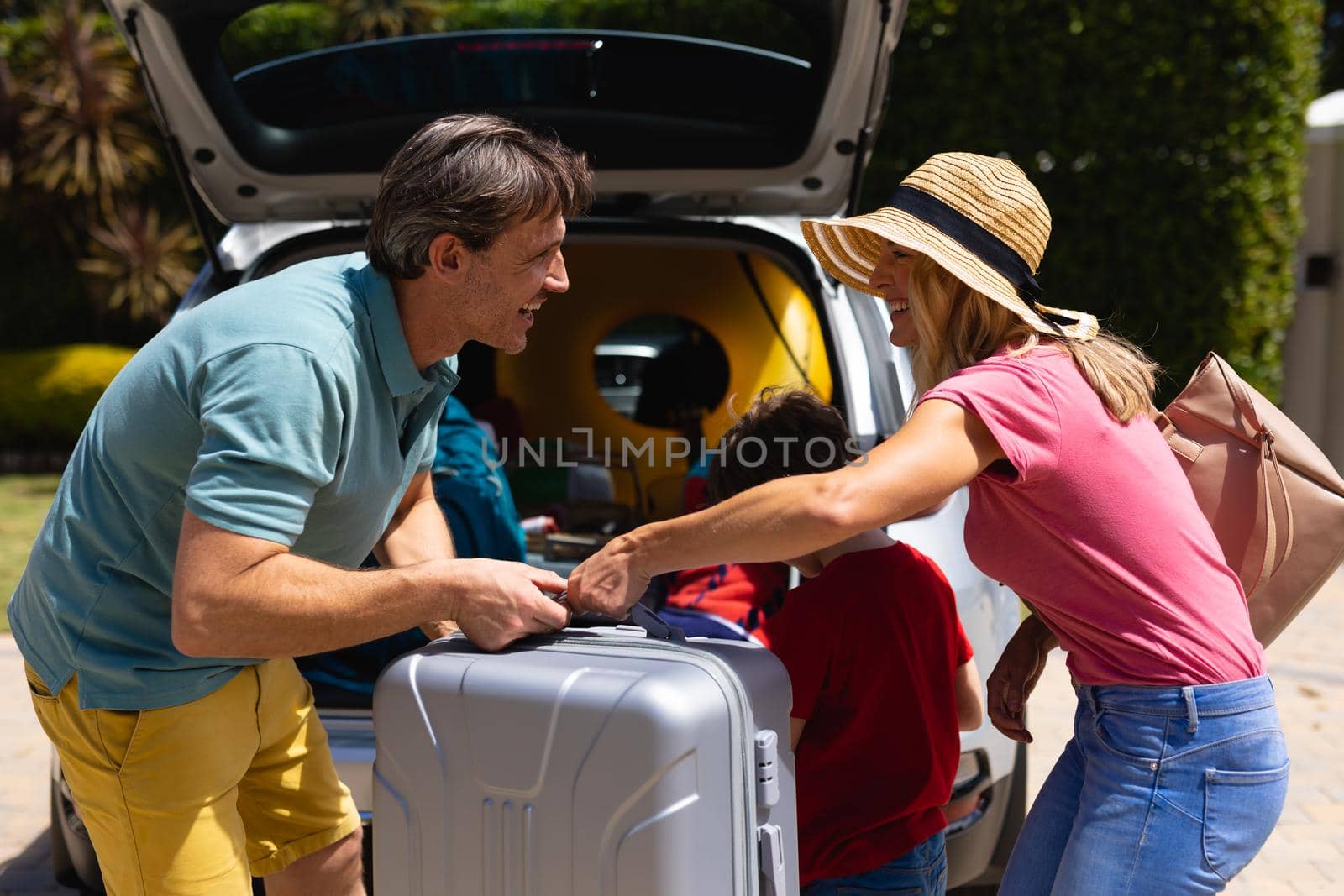 Happy caucasian family putting their luggage in their car on sunny day by Wavebreakmedia