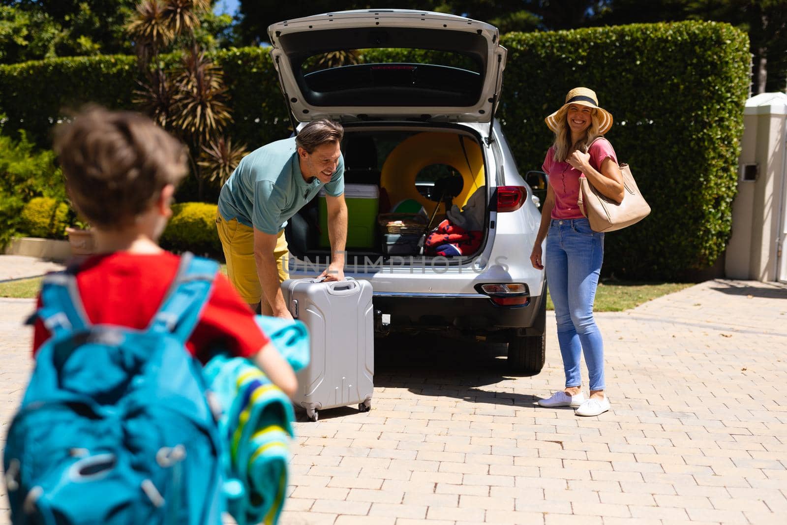 Happy caucasian family putting their luggage in their car outdoors. family trip and vacation concept, unaltered.