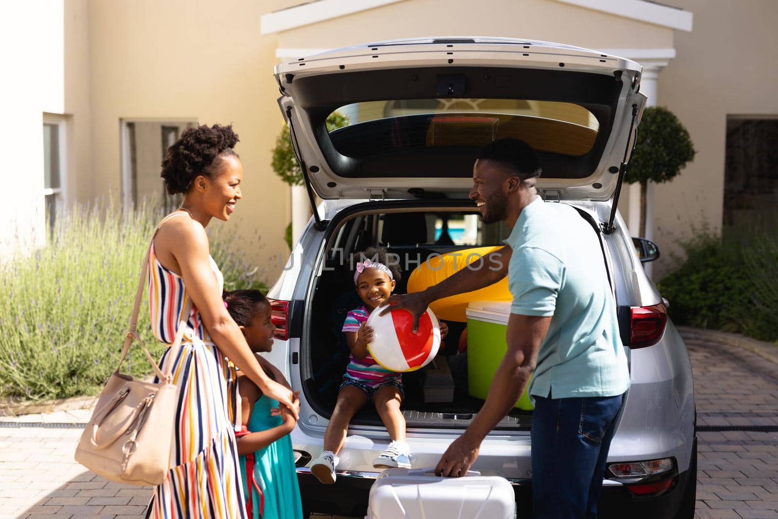 African american family smiling while standing near their car outdoors. family trip and vacation concept, unaltered.