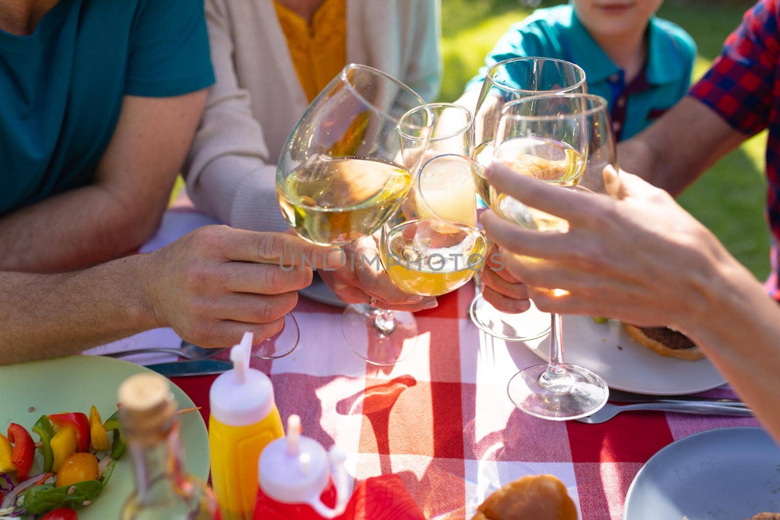 Midsection of caucasian family toasting drinks at table in garden by Wavebreakmedia