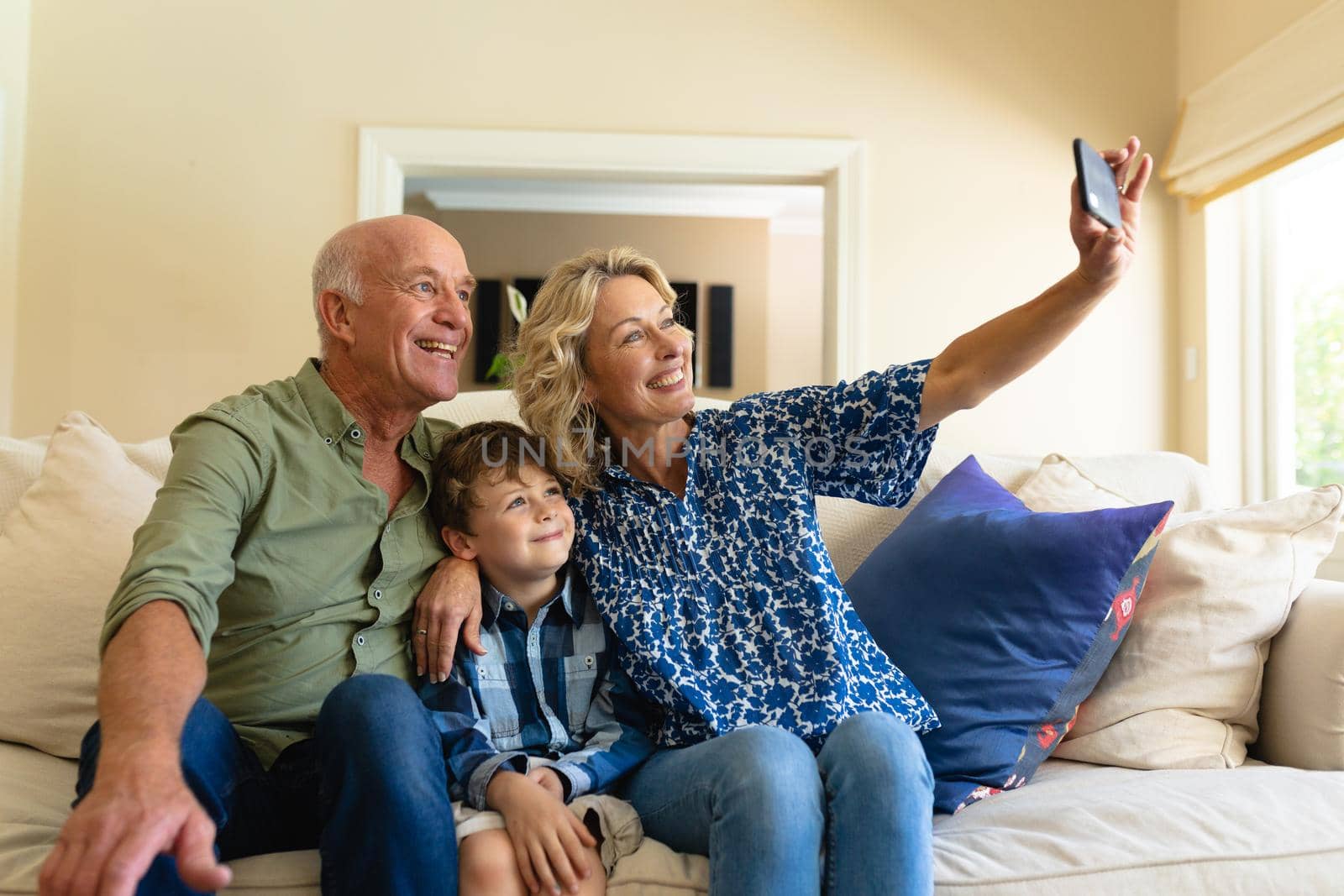 Caucasian grandparents and grandson taking a selfie while sitting together on couch at home by Wavebreakmedia
