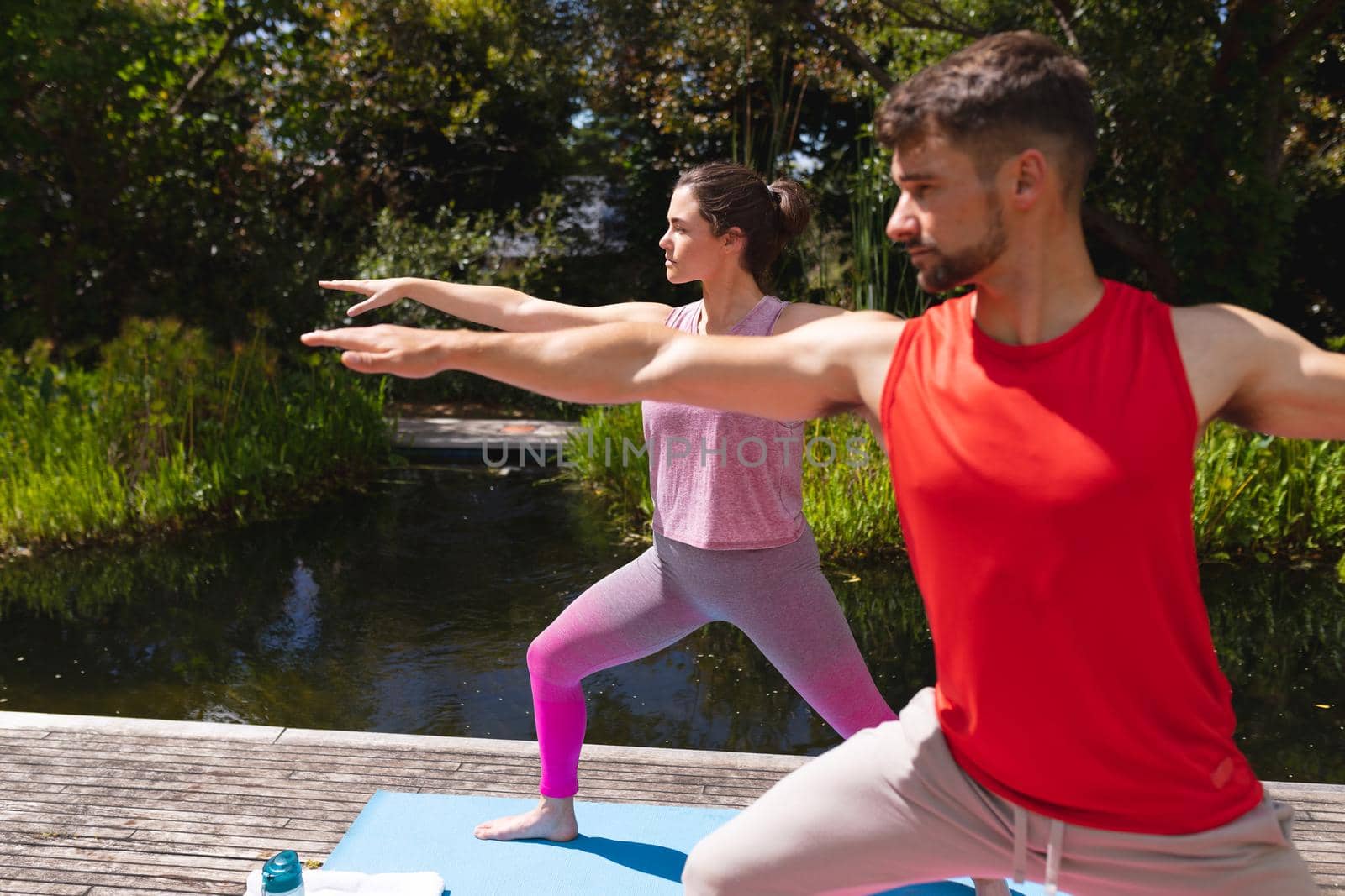 Young man and woman exercising together in park on sunny day by Wavebreakmedia