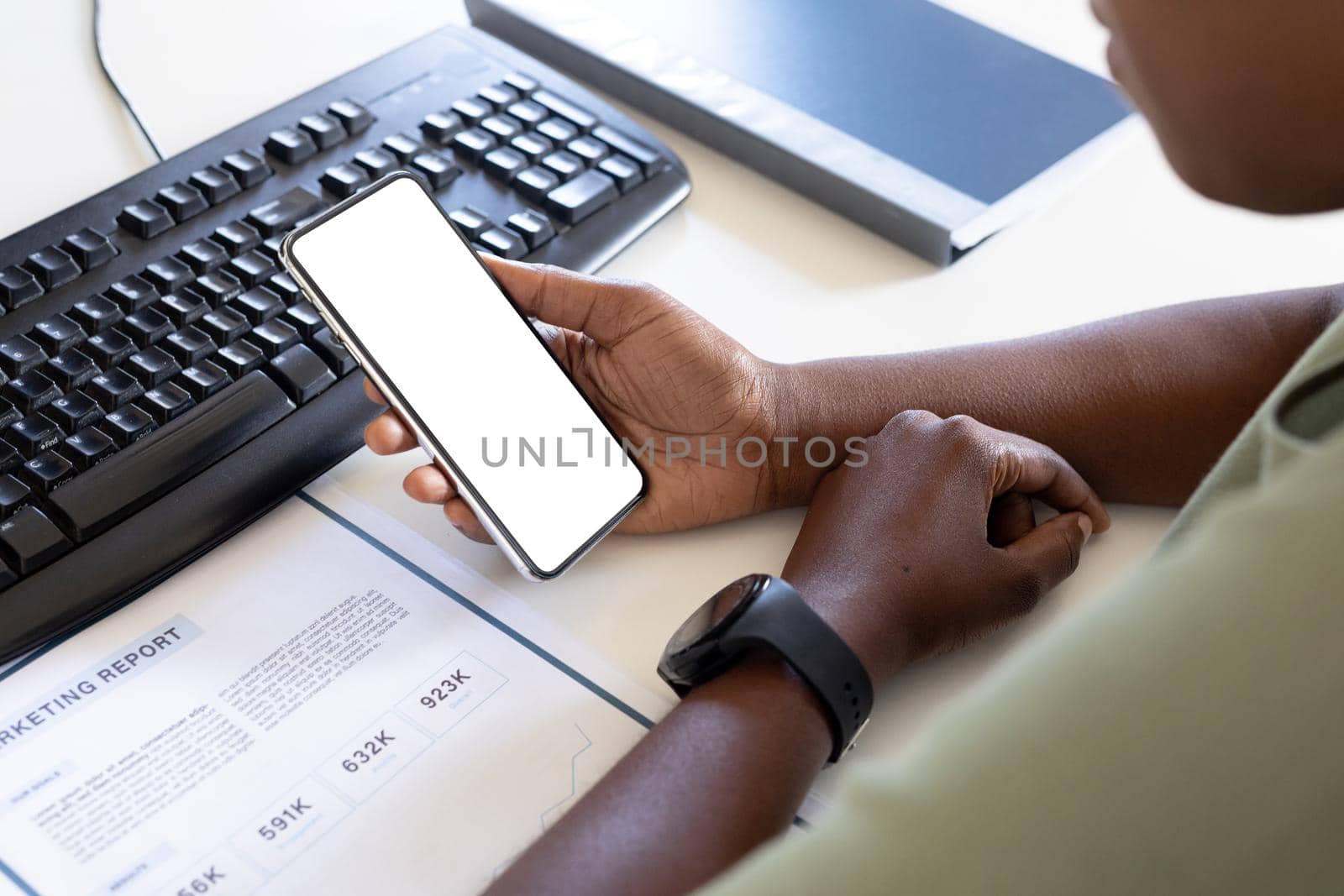 Cropped image of female professional using smart phone with copy space at computer desk in office. unaltered, creative business and wireless technology concept.