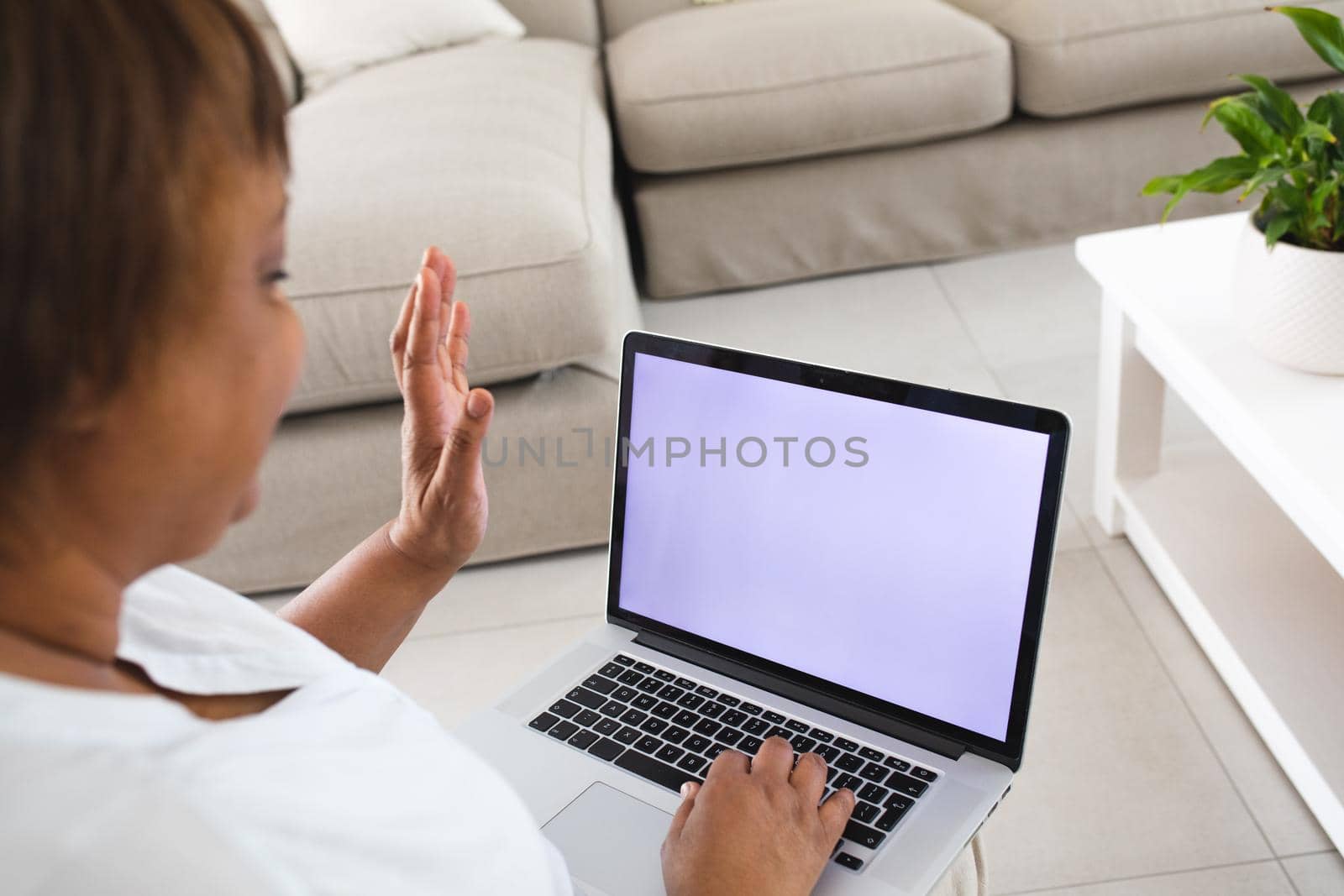 African american senior woman waving hand during video call on laptop with copy space at home. lifestyle, wireless technology, communication and advertisement.