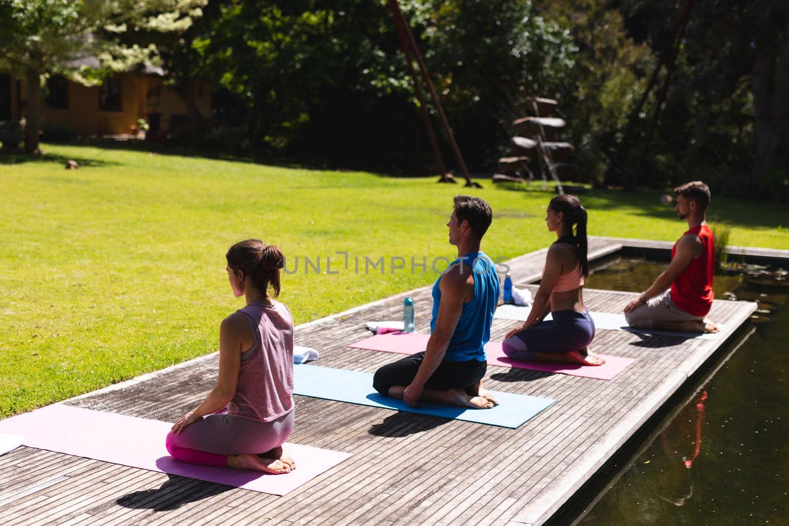 Full length of men and women meditating on floorboard in park. yoga, healthy lifestyle and body care.