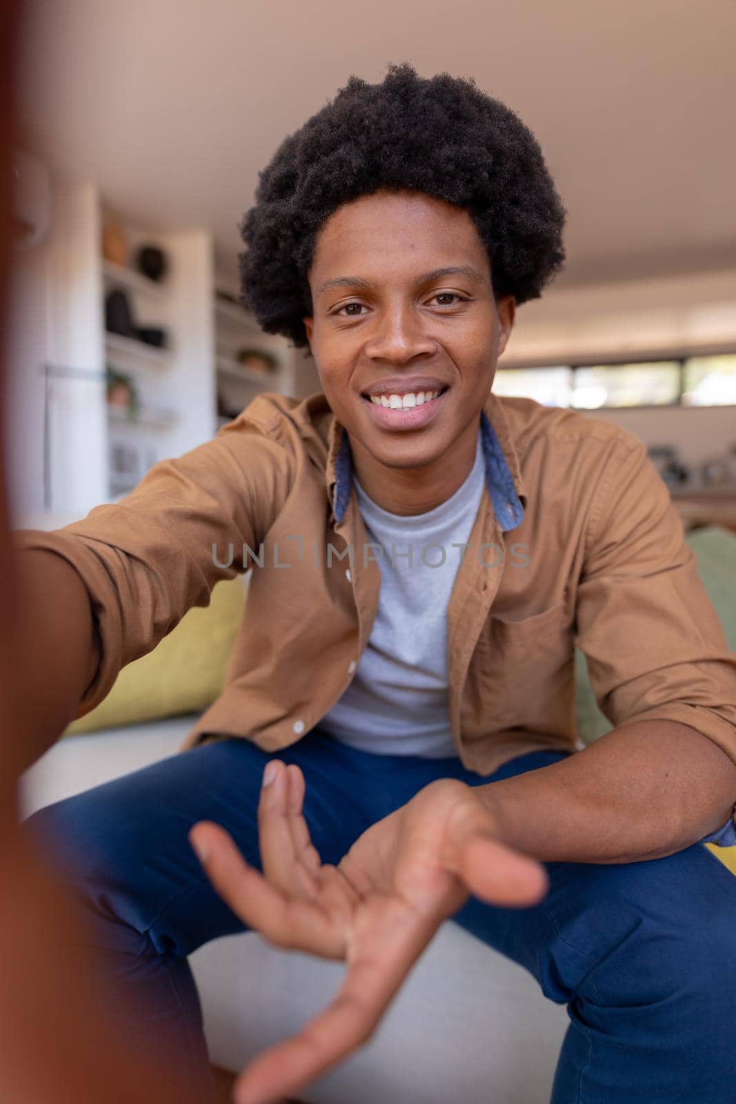 Portrait of smiling african american young man gesturing during video call while sitting at home by Wavebreakmedia