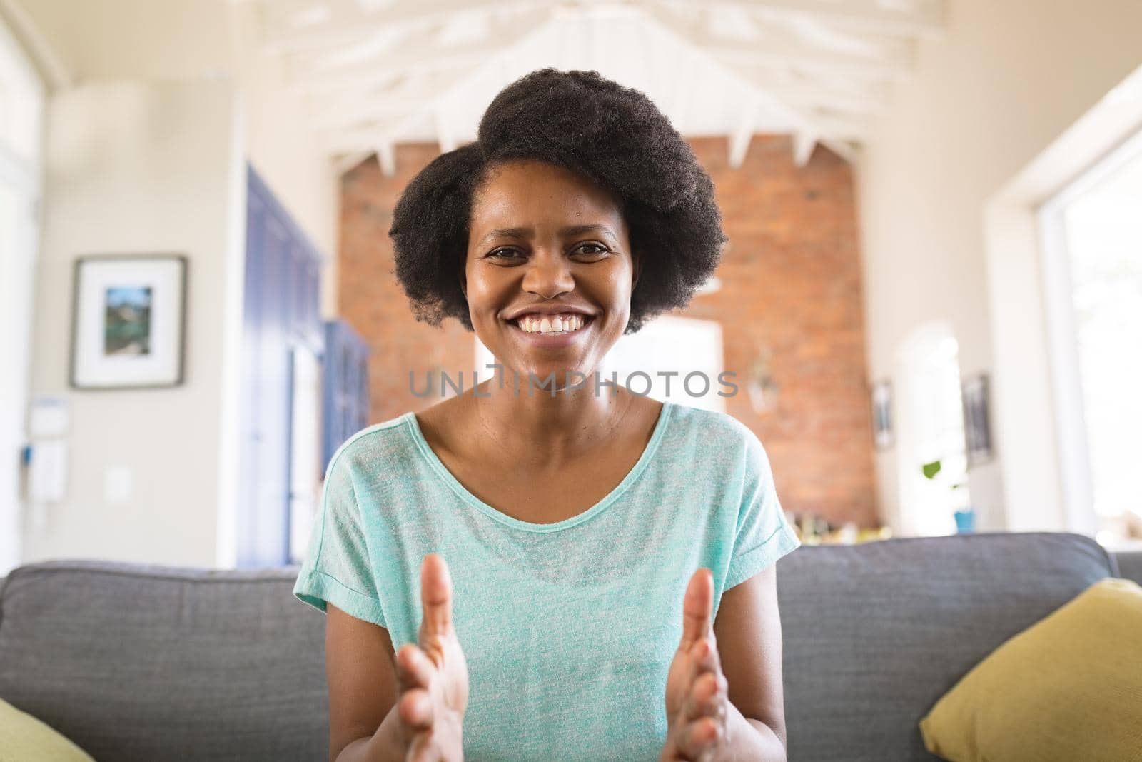 Portrait of cheerful african american woman gesturing while explaining on video call at home. influencer, communication and vlogging concept.