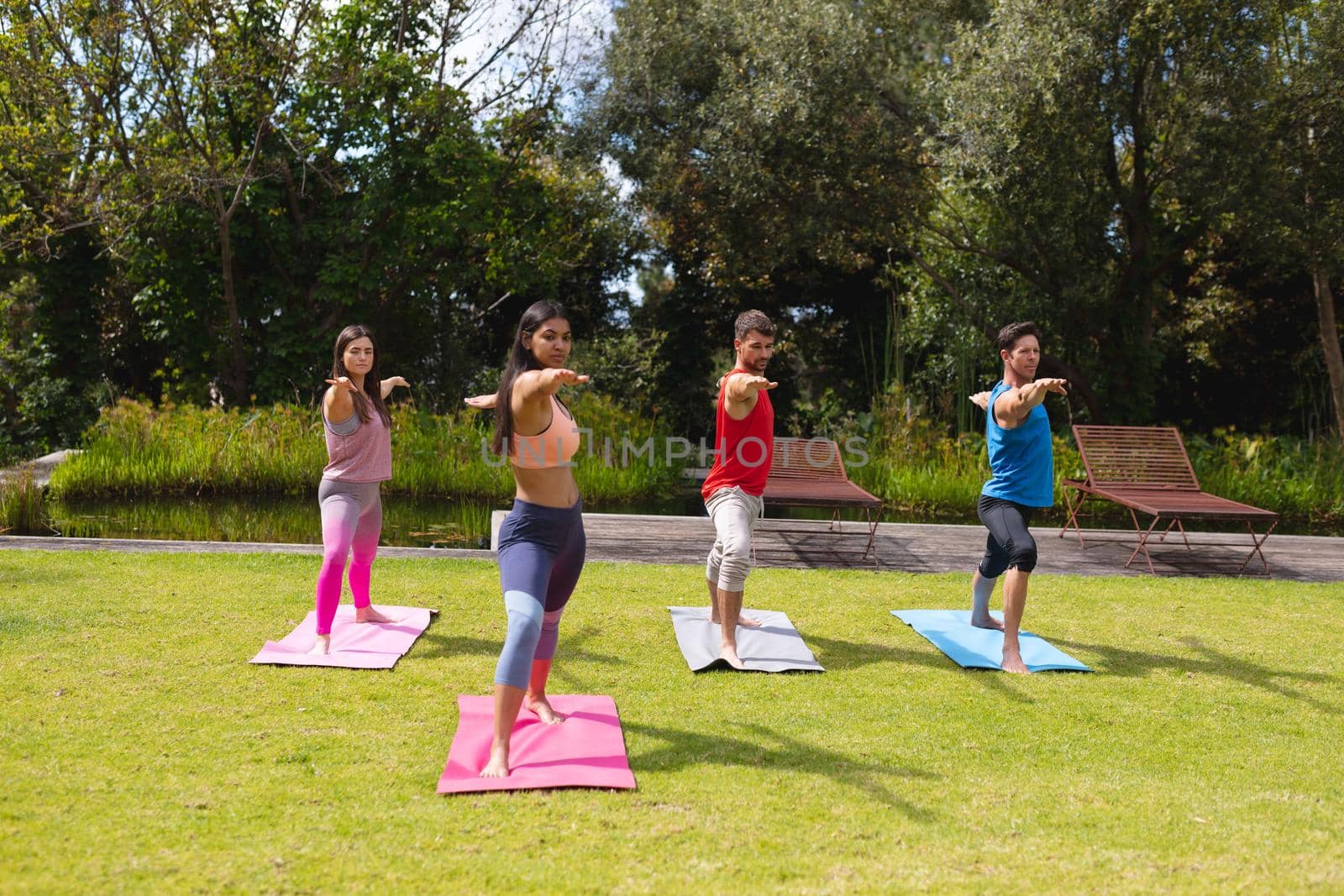 Female instructor teaching exercise to men and woman in public park by Wavebreakmedia