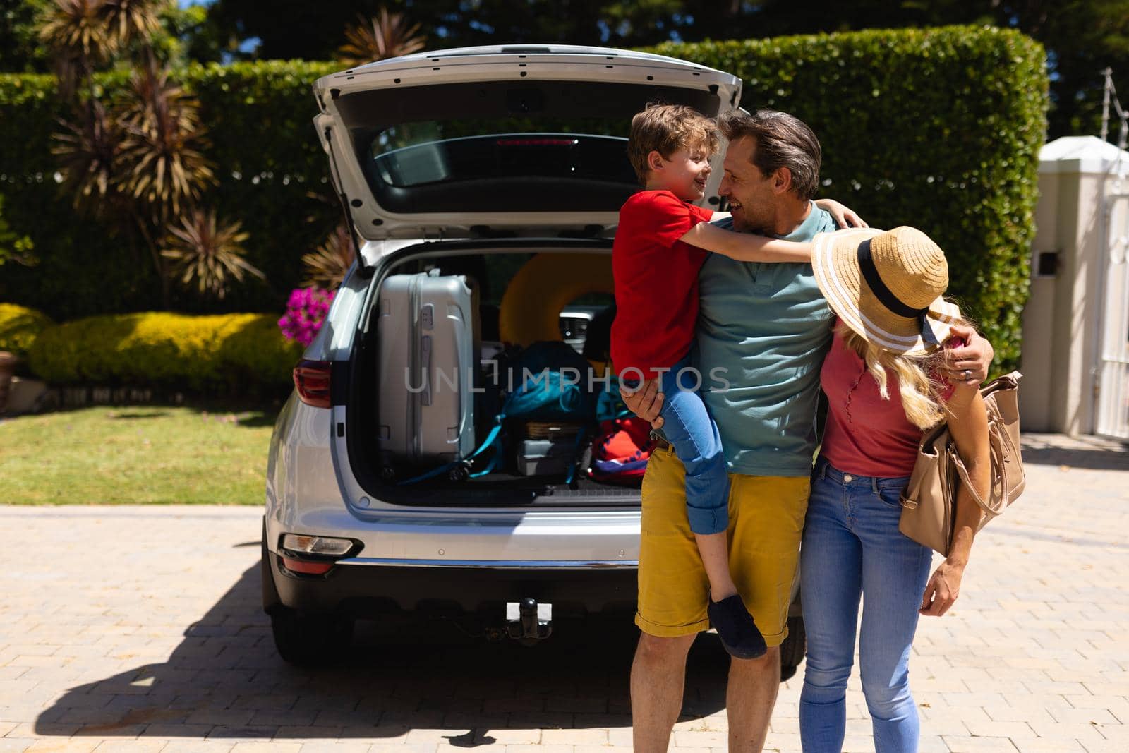 Caucasian family standing near their car smiling looking at each others by Wavebreakmedia