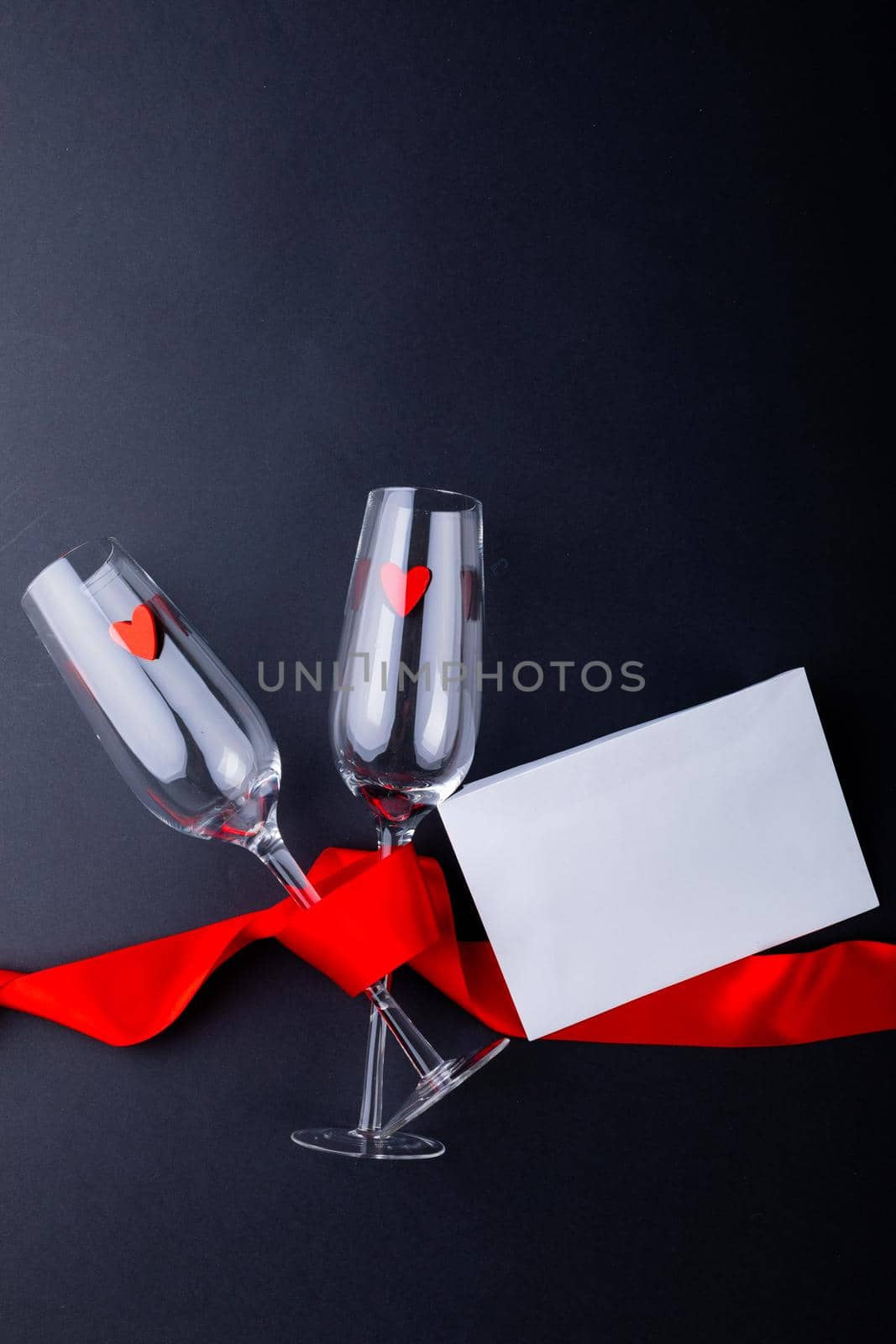 Empty champagne flutes tied with red ribbon by envelope isolated on gray background, copy space. valentine's day and love concept.