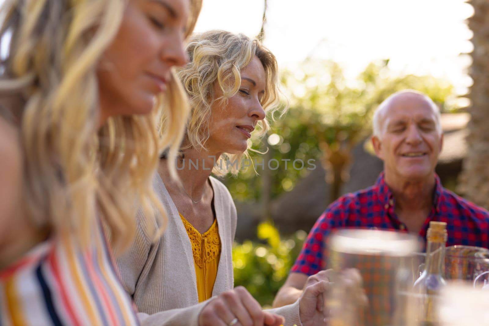 Caucasian mother and father with daughter praying at the garden. family, togetherness and weekend lifestyle concept, unaltered.