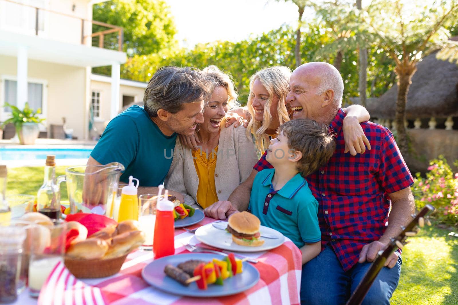 Cheerful caucasian three generational family laughing while sitting together in garden. family, togetherness and weekend lifestyle concept, unaltered.
