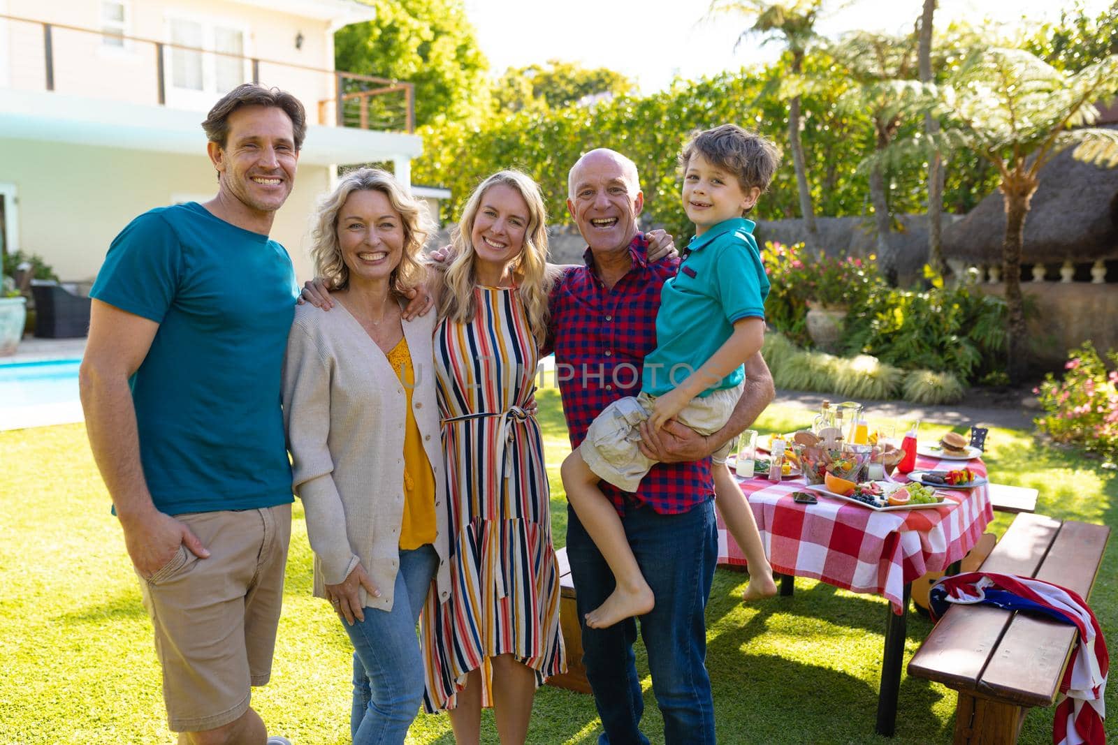 Portrait of smiling three generational caucasian family standing together in garden. family, togetherness and weekend lifestyle concept, unaltered.