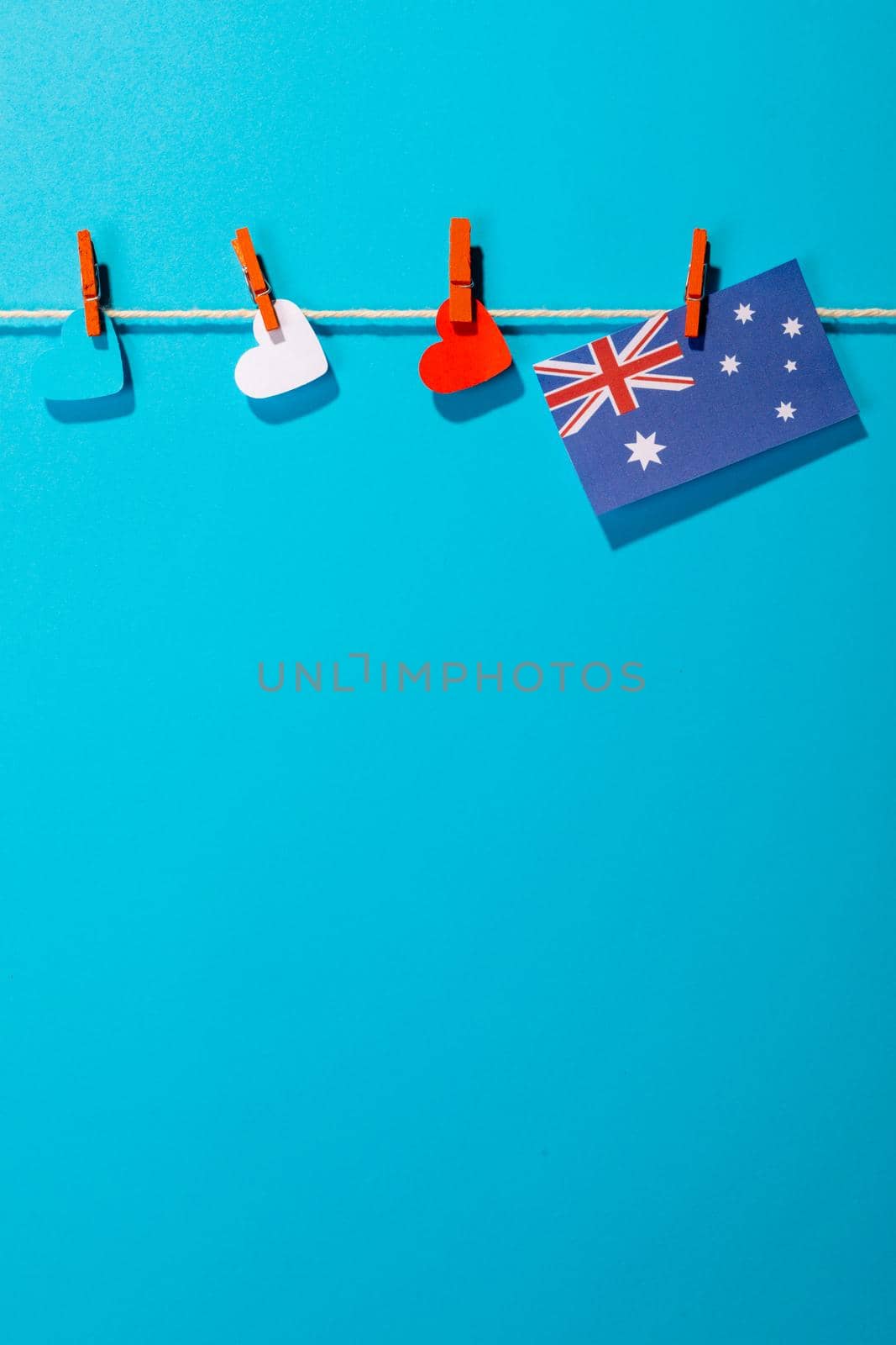 Australia flag and heart shapes hanging on clothesline with copy space against blue background by Wavebreakmedia