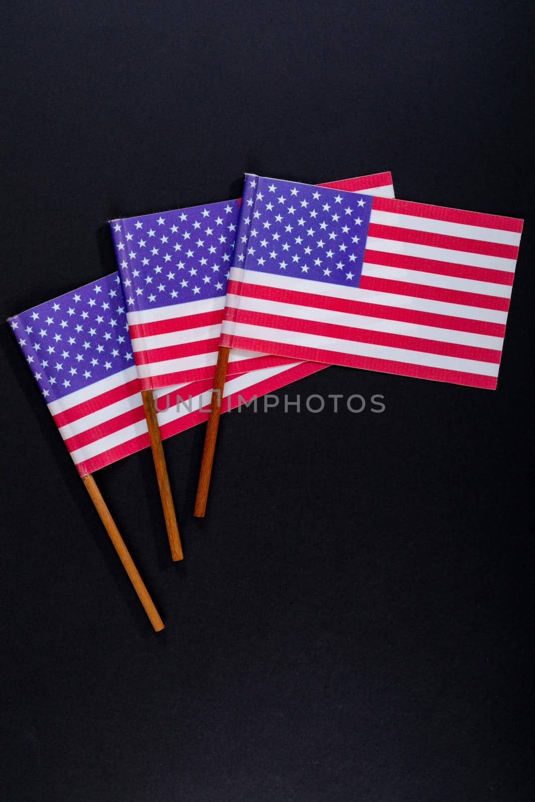 Red and white stripes along with stars on america flag sticks on black background by Wavebreakmedia
