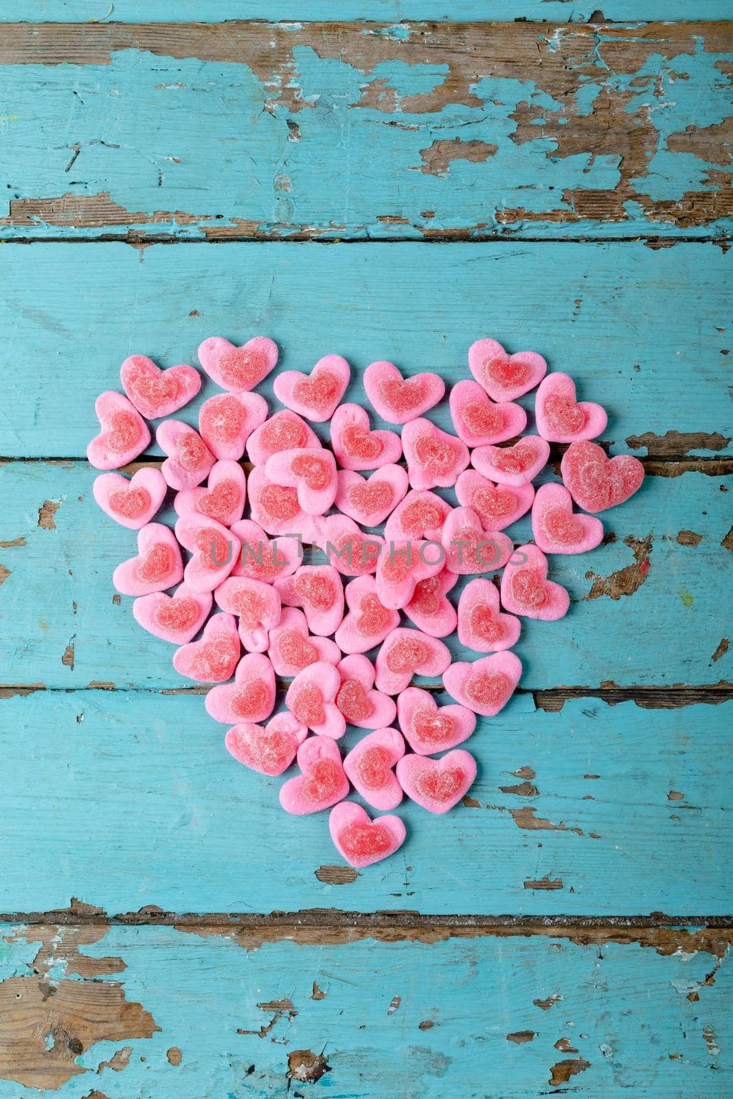 Overhead view of heart shaped pink candies arranged on wooden table, copy space. valentine's day, sweet food and love concept.