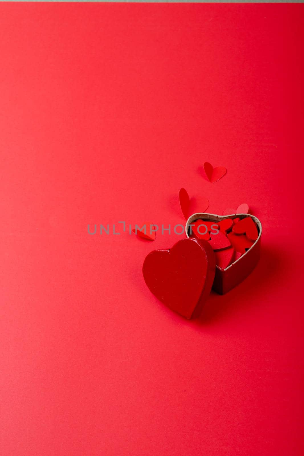 High angle view of heart shaped decoration and gift box on red background, copy space by Wavebreakmedia