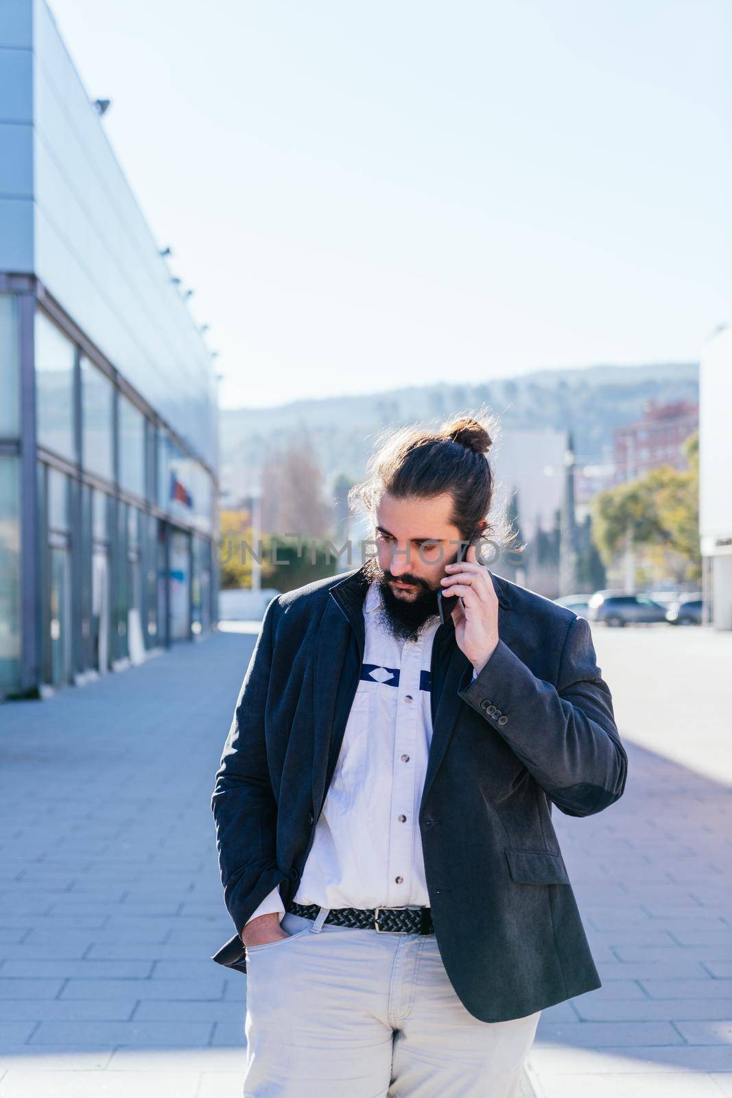 Young business man talking mobile next to the offices by CatPhotography