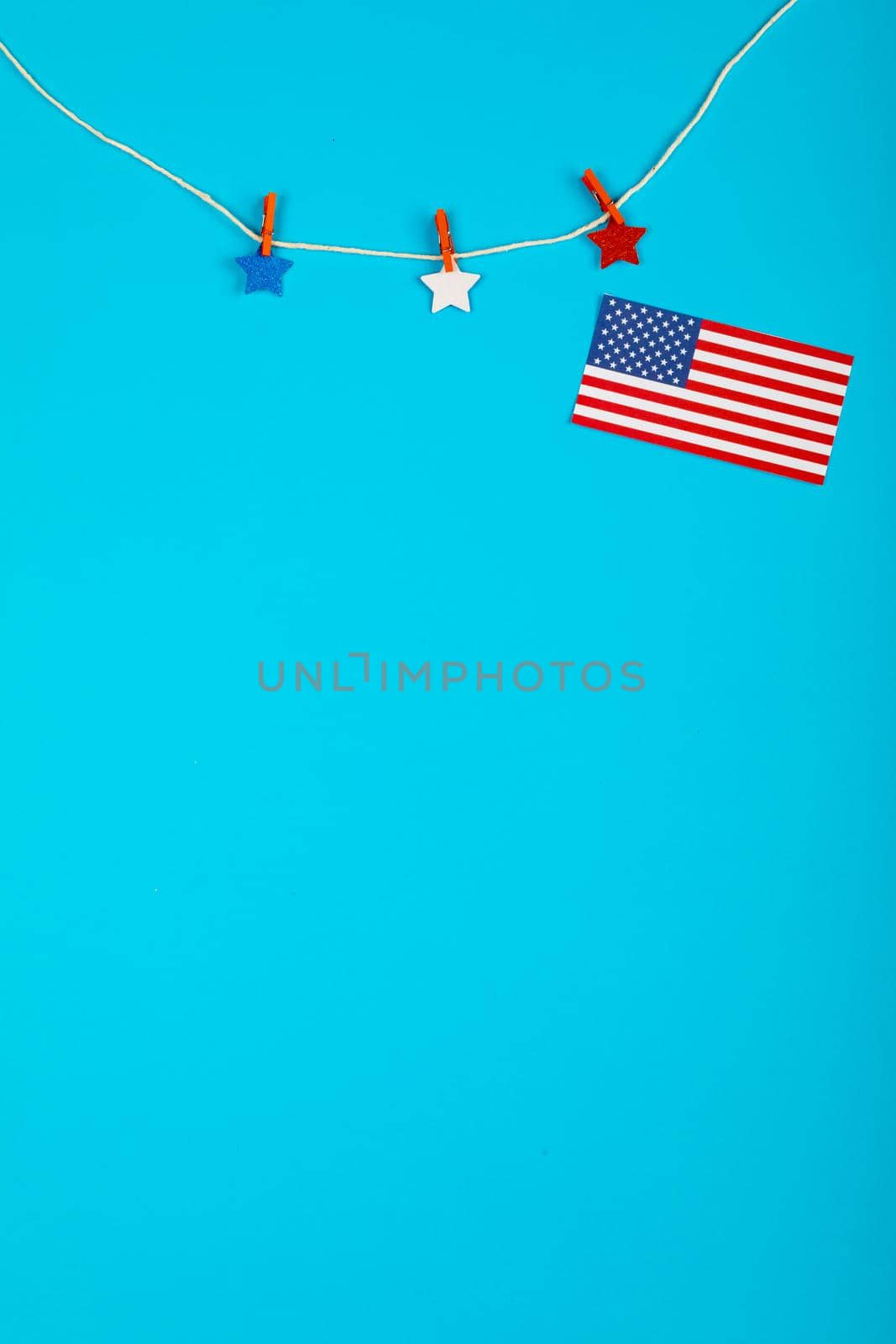 Clothespin with stars and detached usa flag hanging from string over blue background with copy space. patriotism, symbol and identity.